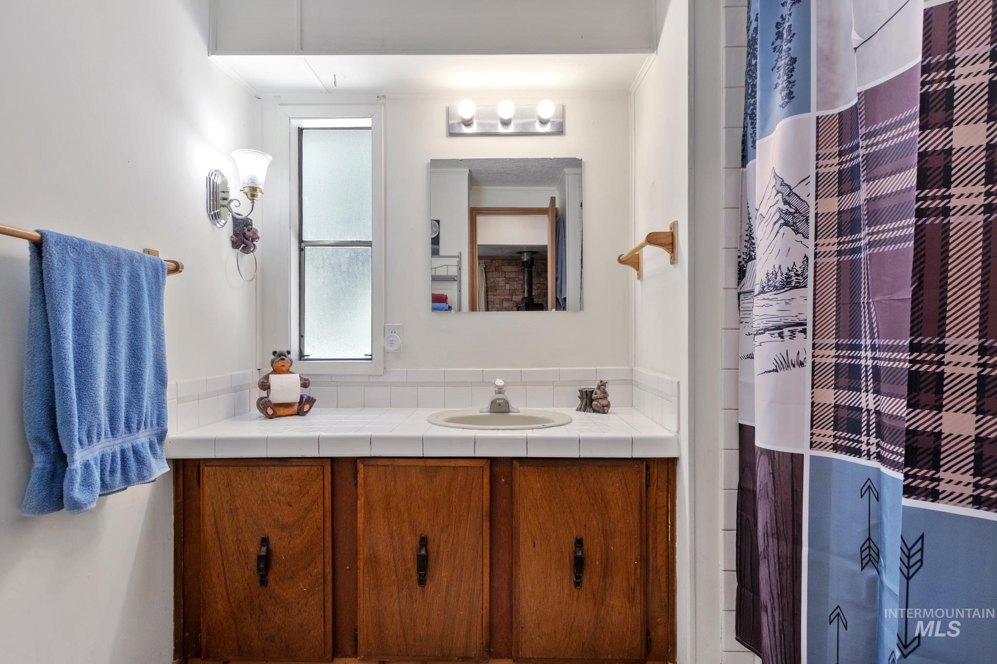 Bathroom vanity featuring wood cabinetry, a tiled countertop, and an integrated sink basin