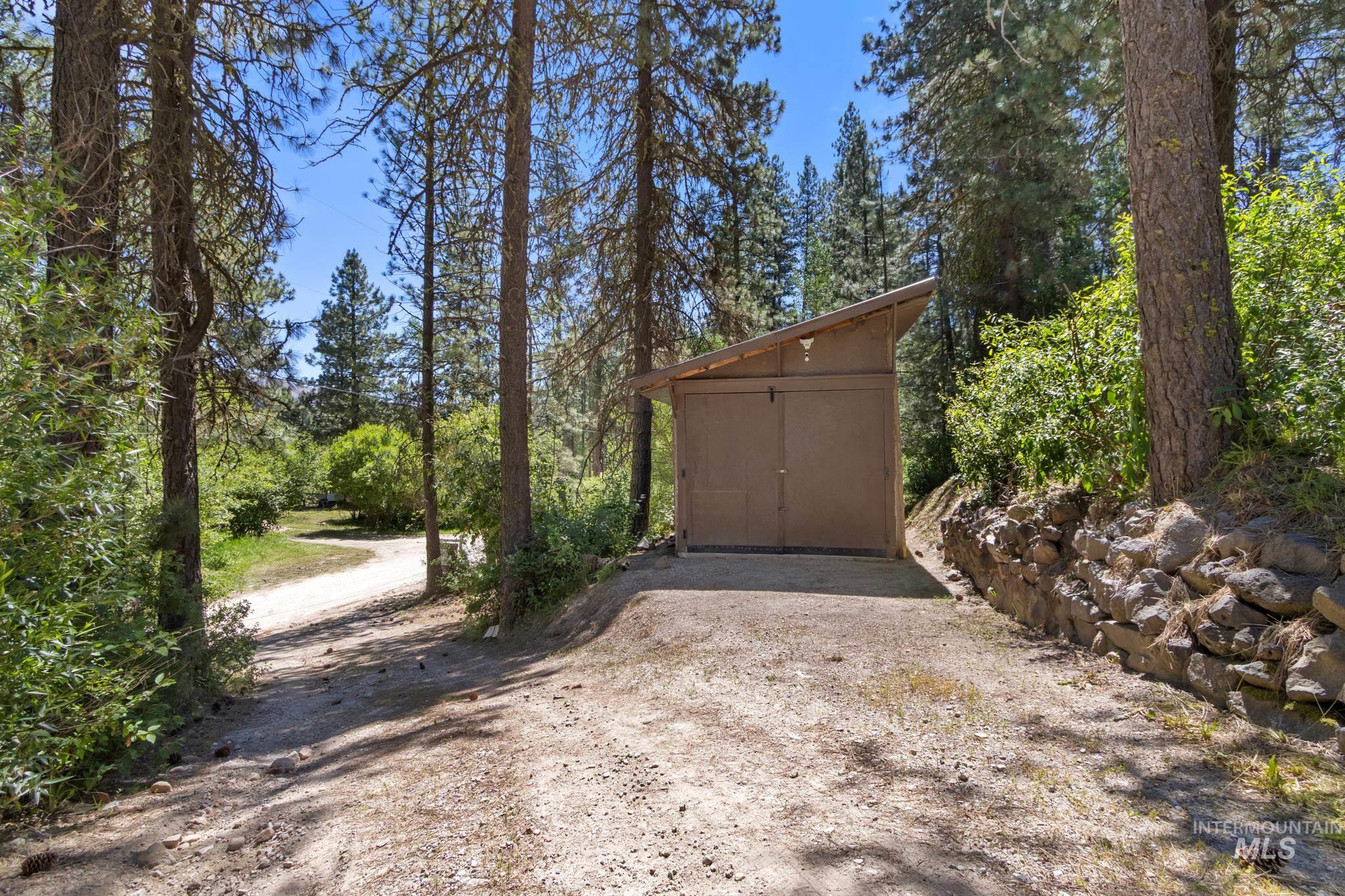 Freestanding outbuilding with a lean-to roof, two large sliding doors, and exterior lighting