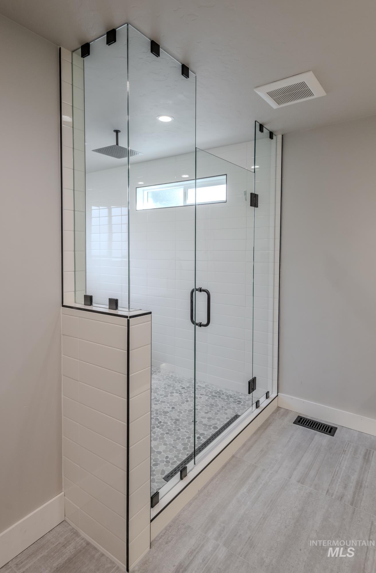 Bathroom featuring a wet-room shower with multiple shower heads, freestanding soaker tub, dual vanity, recessed lighting, backlit mirror and light wood flooring