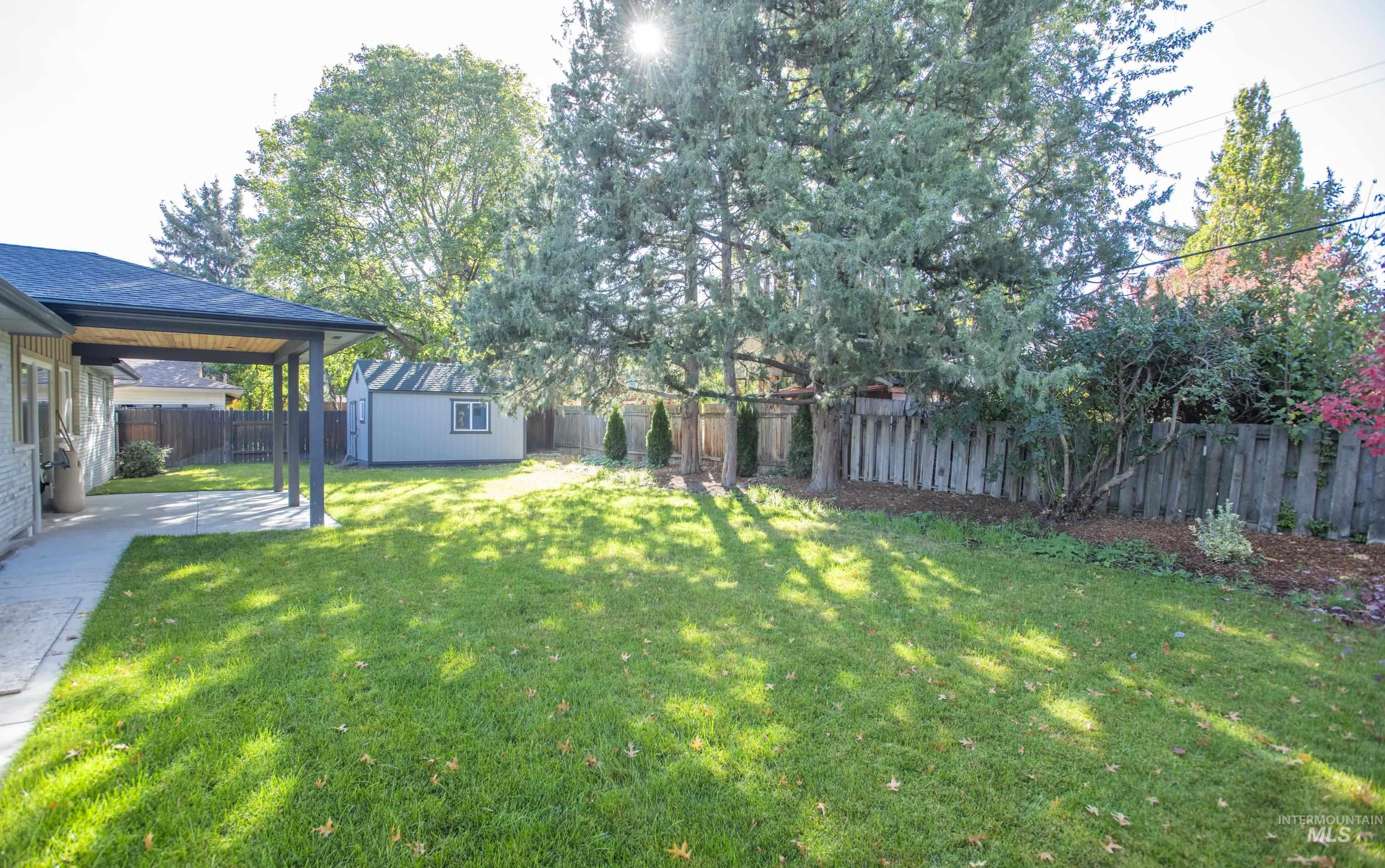 Fenced backyard featuring a storage shed and a patio area