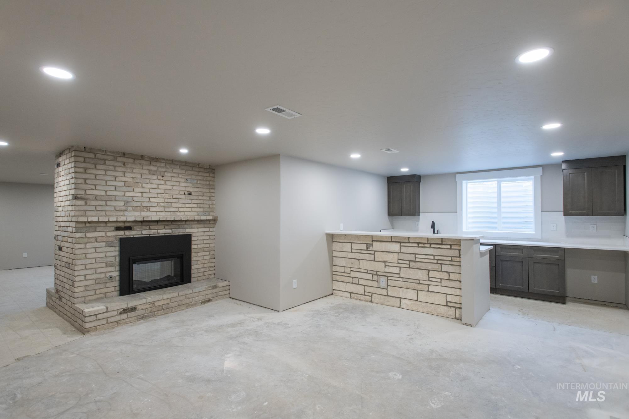 Lower level living room featuring, a brick double sided fireplace, wet bar and recessed lighting