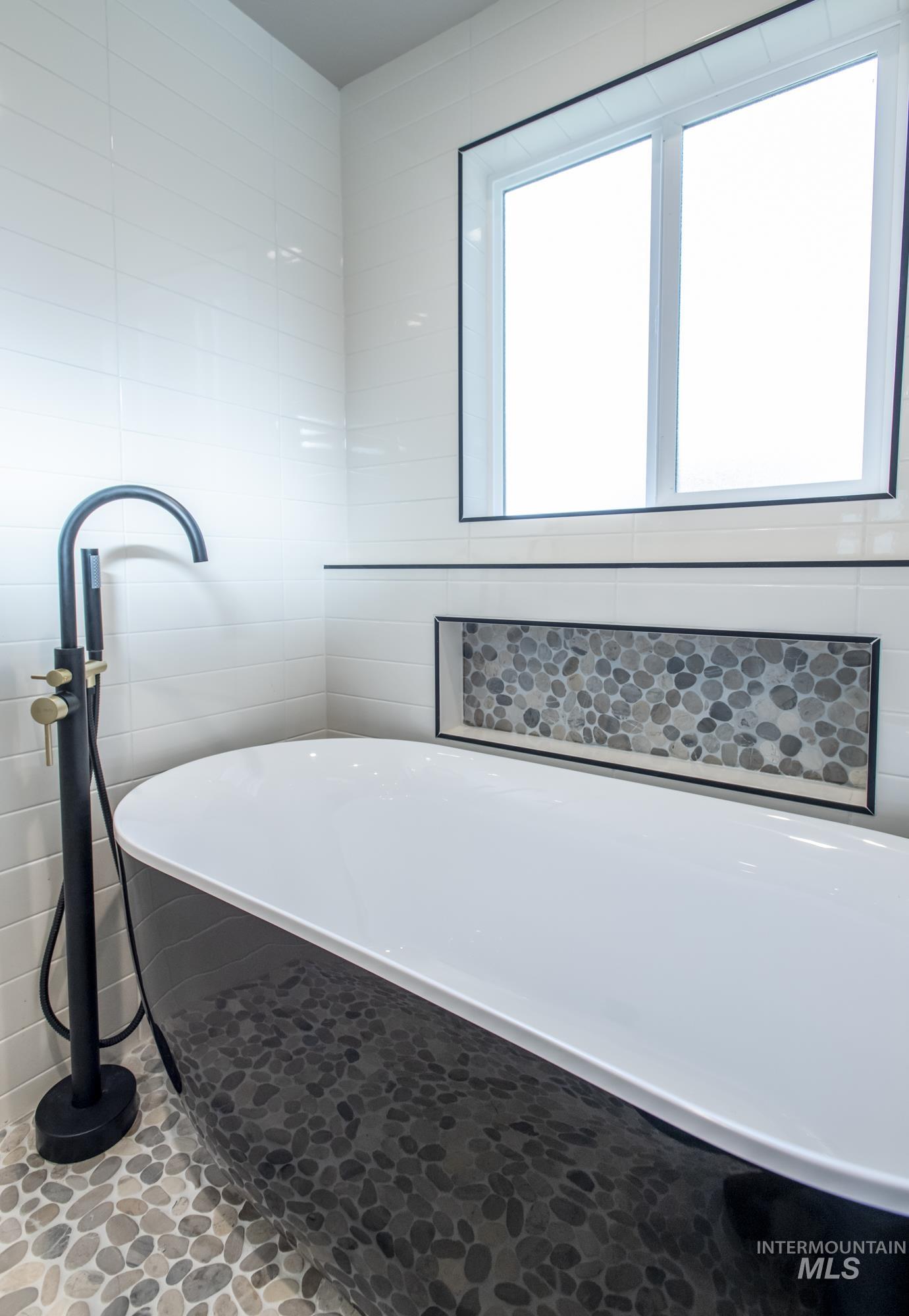Soaker tub bath featuring a freestanding bath, freestanding filler, recessed lighting, and tile walls.