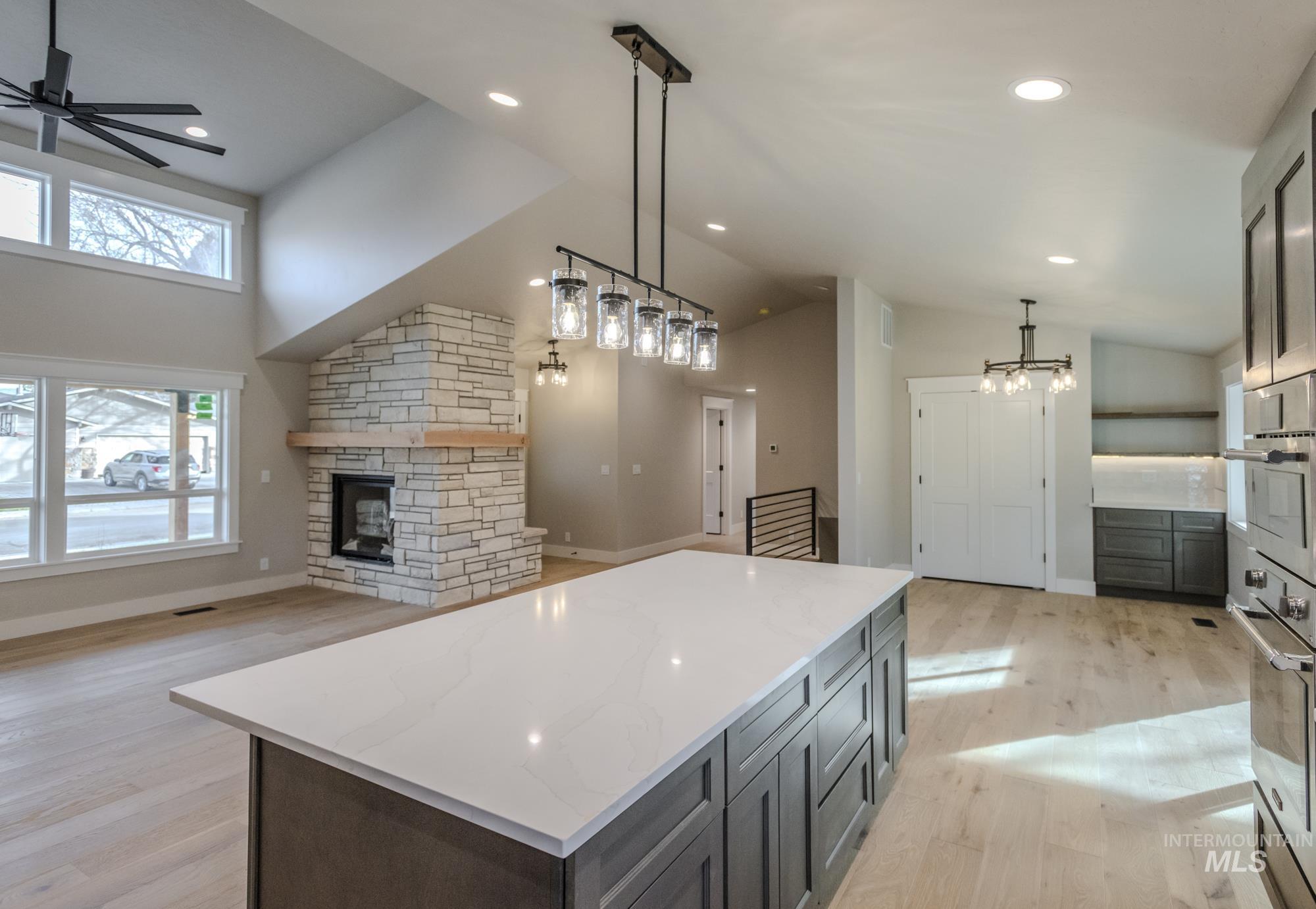 Kitchen featuring a fireplace, light wood-style flooring, pendant lighting, a kitchen island, and high vaulted ceiling, dormer, lots of natural light, coffee nook and breakfast area.