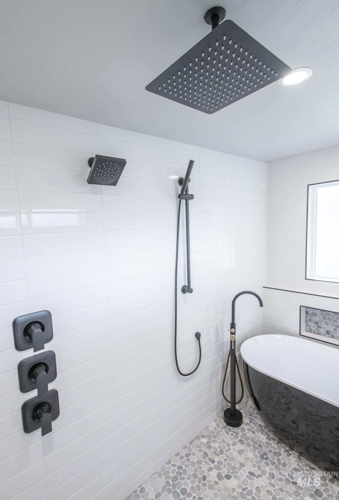 Full bath wet-room with free standing soaking tub and tile shower with multiple shower heads