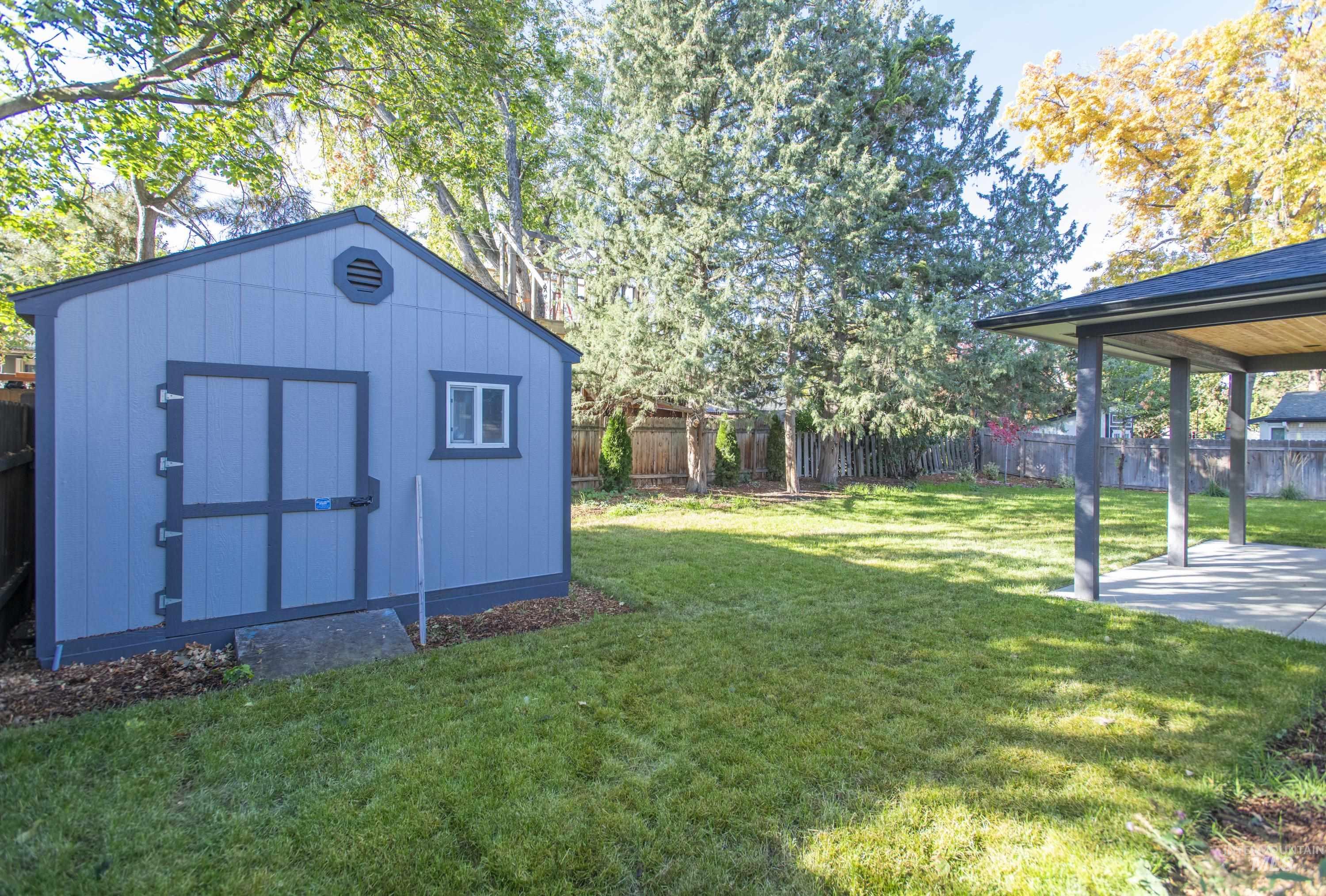 Fenced backyard featuring a storage unit