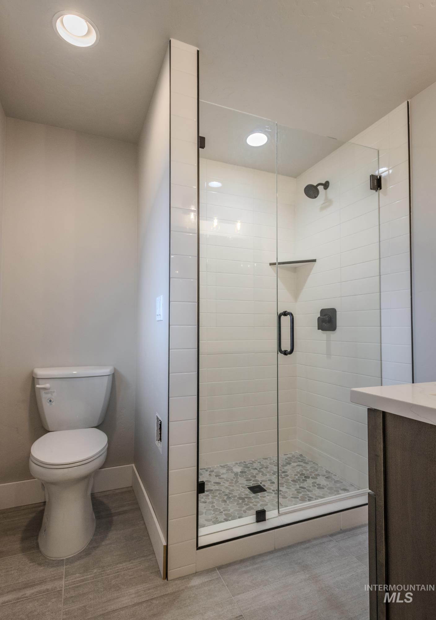 Full bathroom with a shower stall, light tile patterned flooring, recessed lighting, and vanity, off 2nd main floor master.