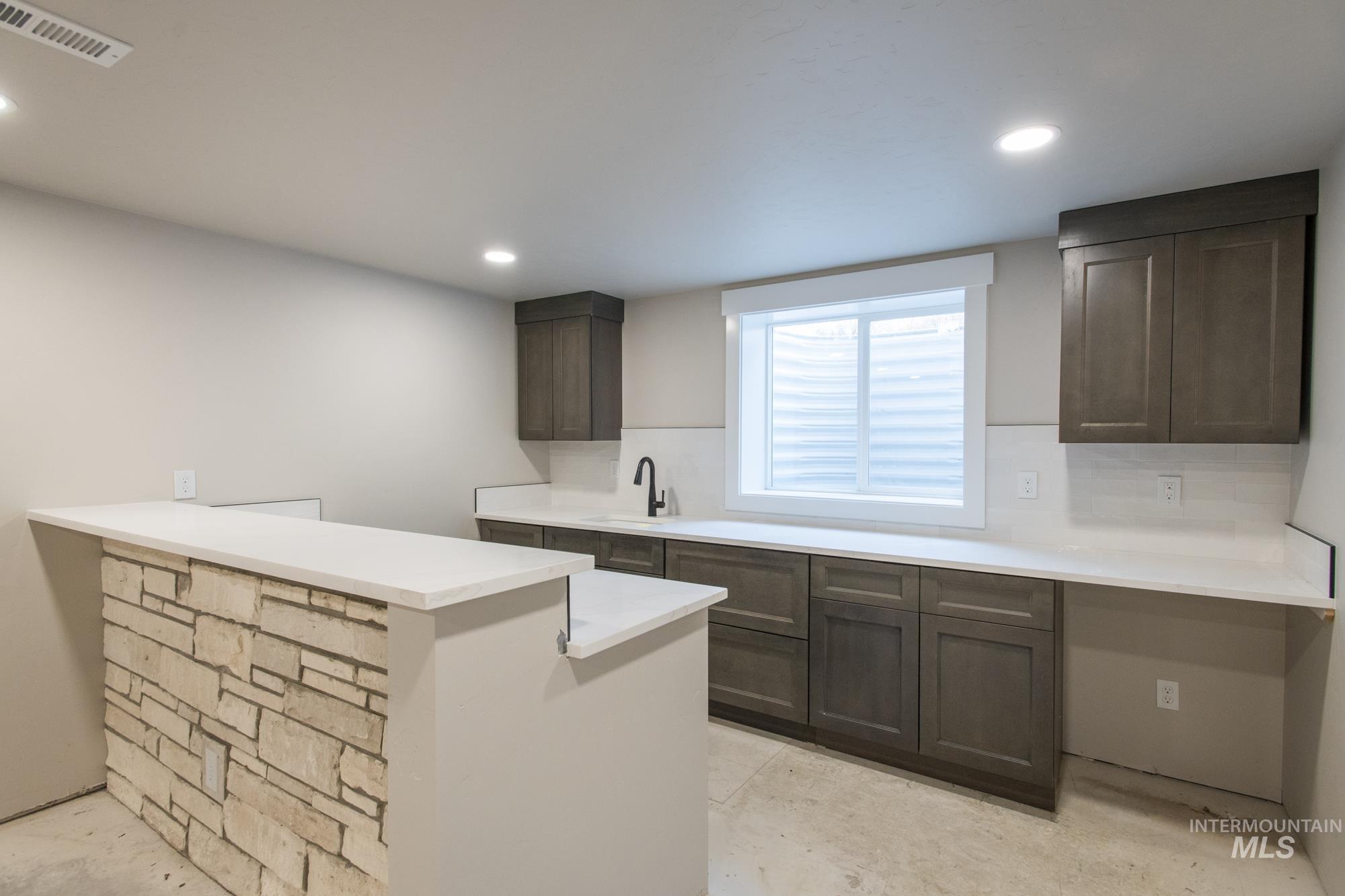 Full wet bar (could be 2nd kitchen) Featuring a peninsula, recessed lighting, light stone countertops.