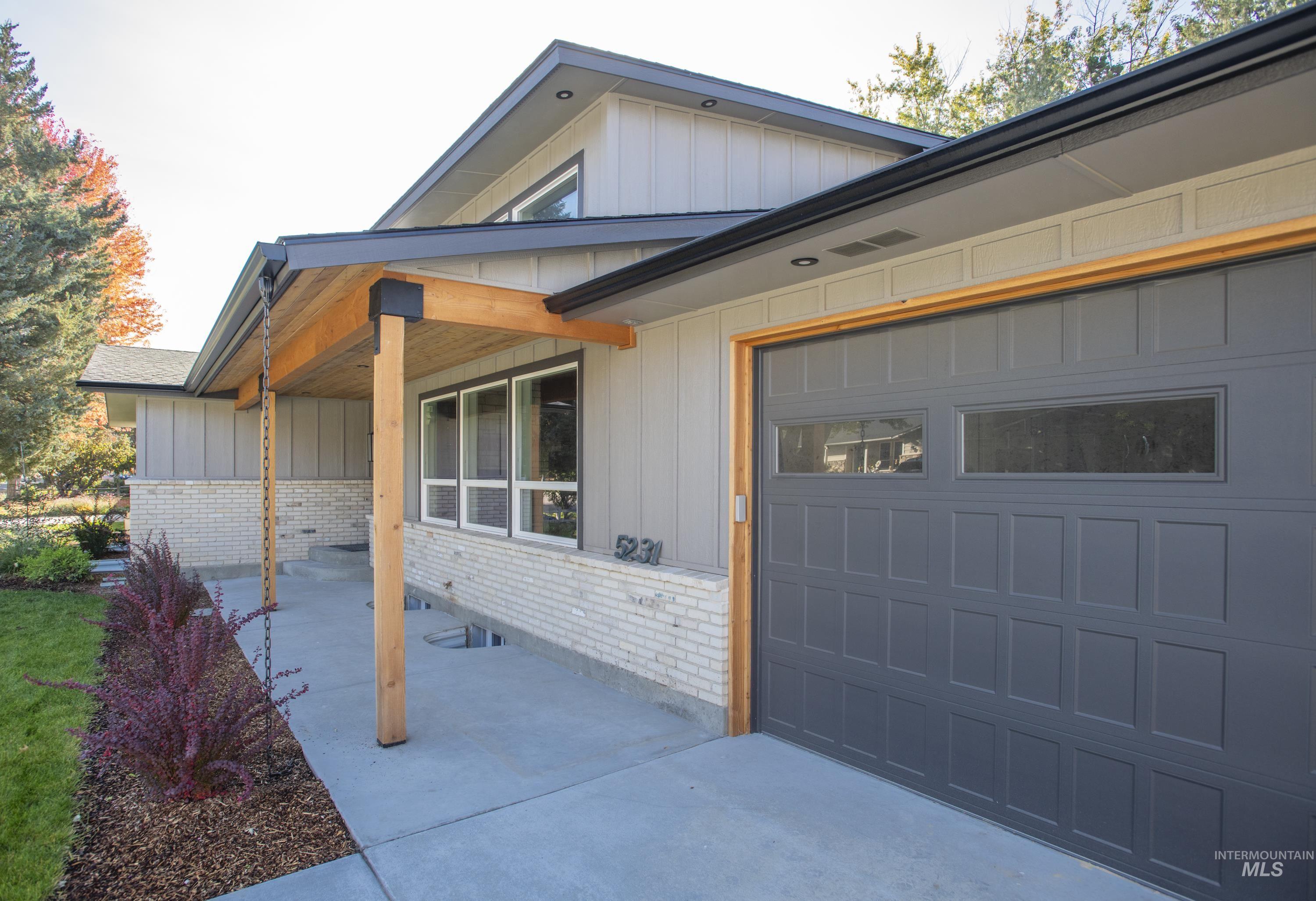 View of front entry to home with ceder covered porch, brick siding, and garage