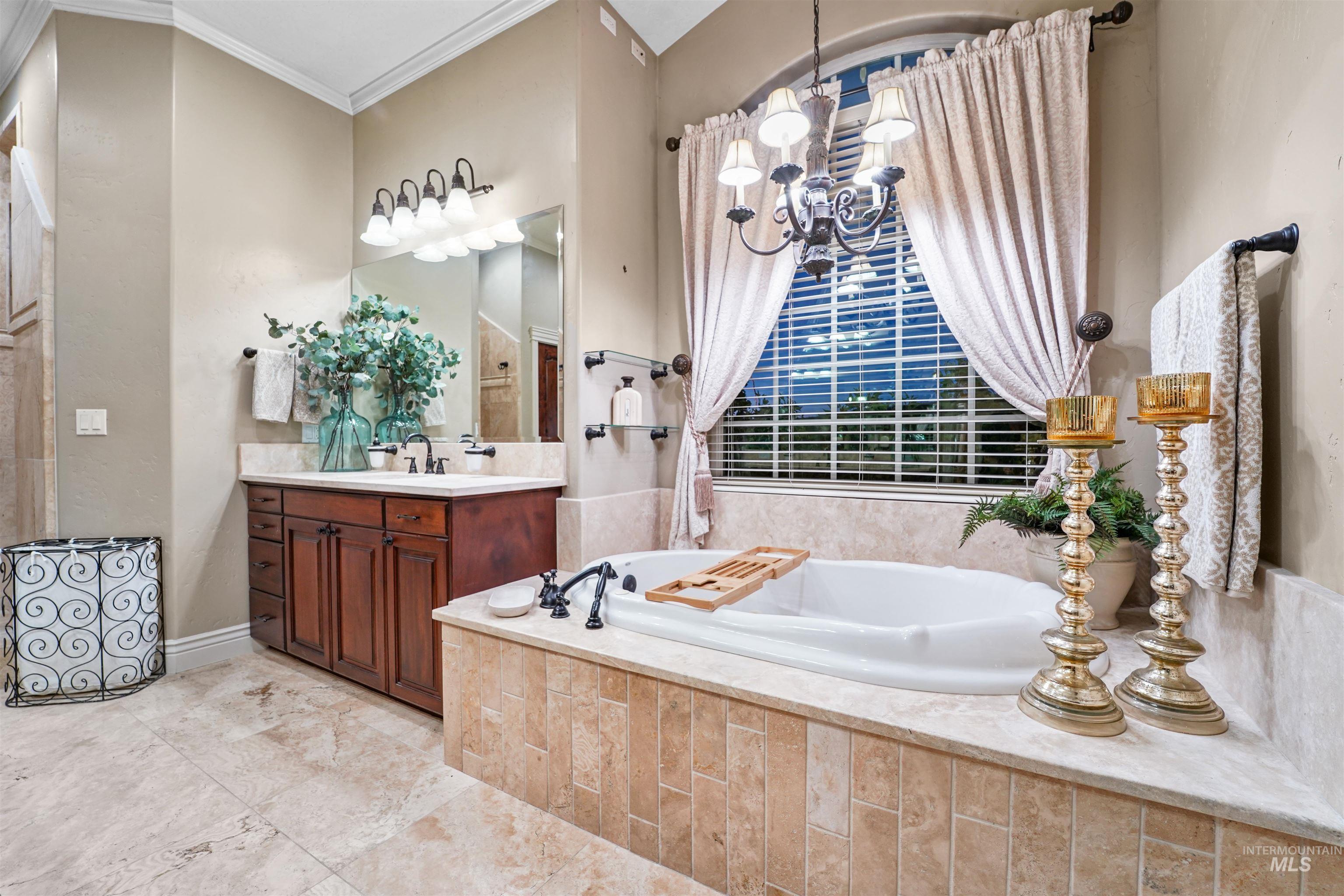 Full bath featuring vanity, a chandelier, a bath, and ornamental molding