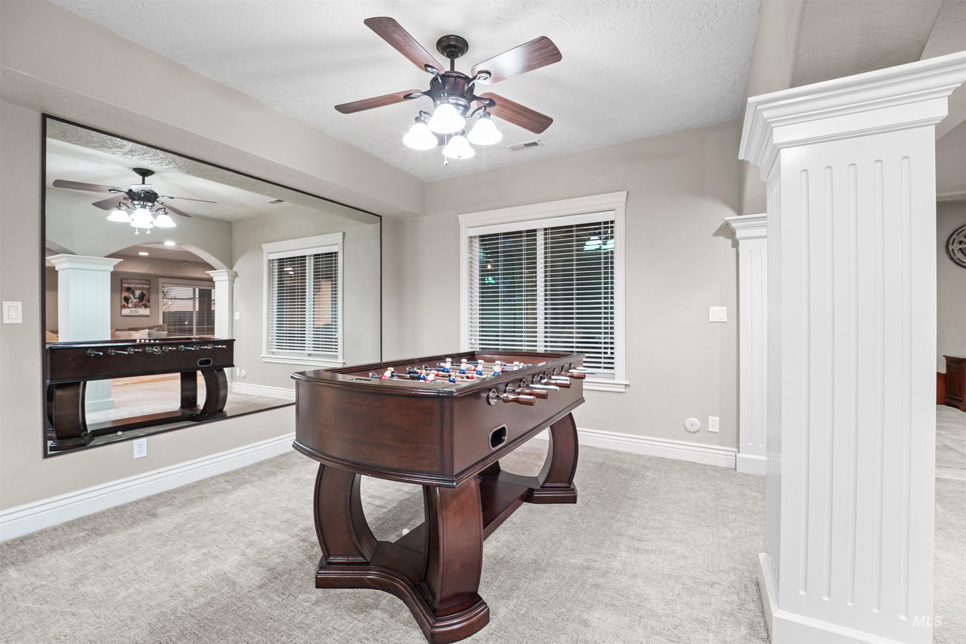 Rec room featuring ornate columns, ceiling fan, and carpet