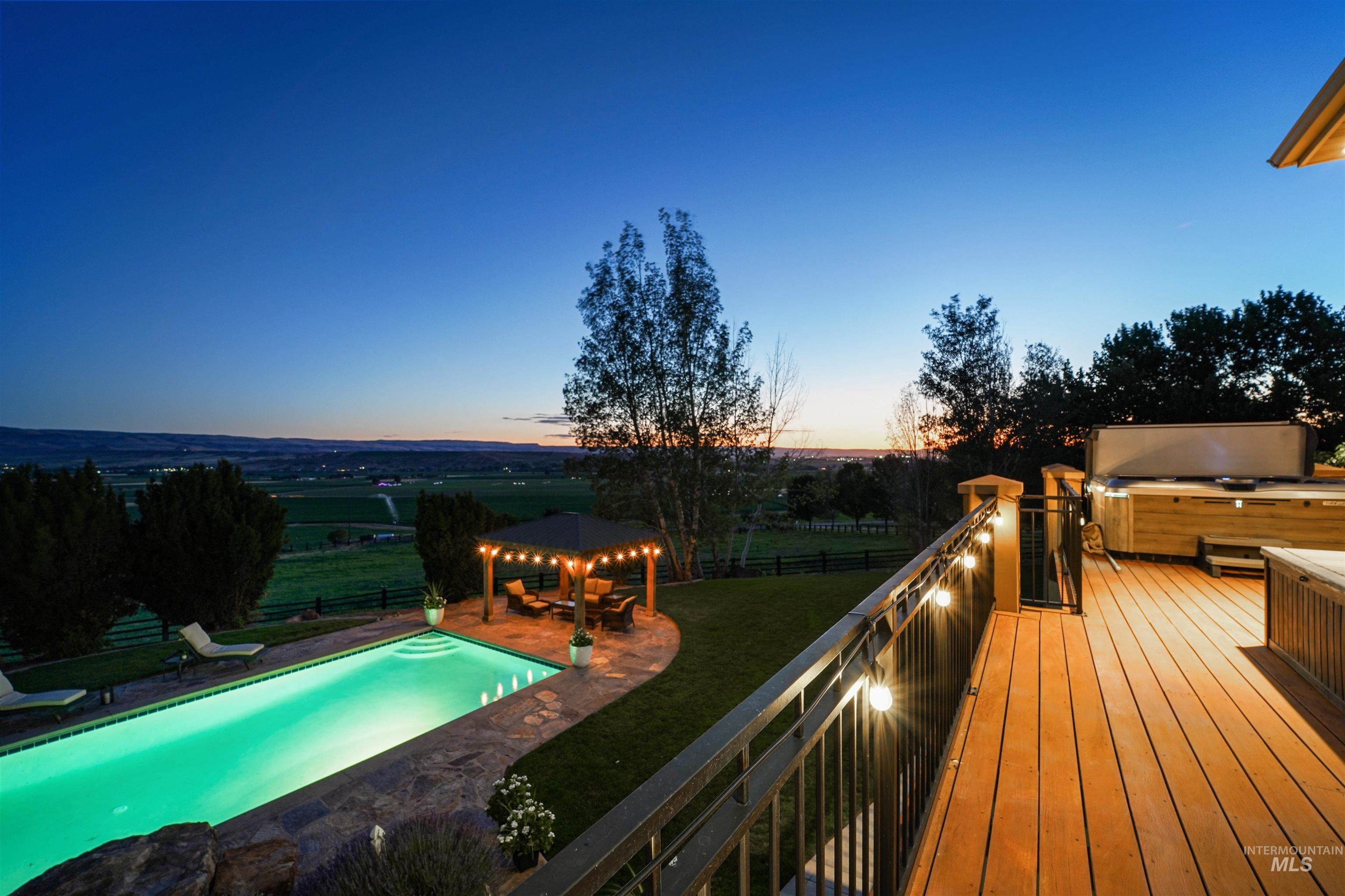Deck at dusk with a gazebo, a hot tub, and a patio area