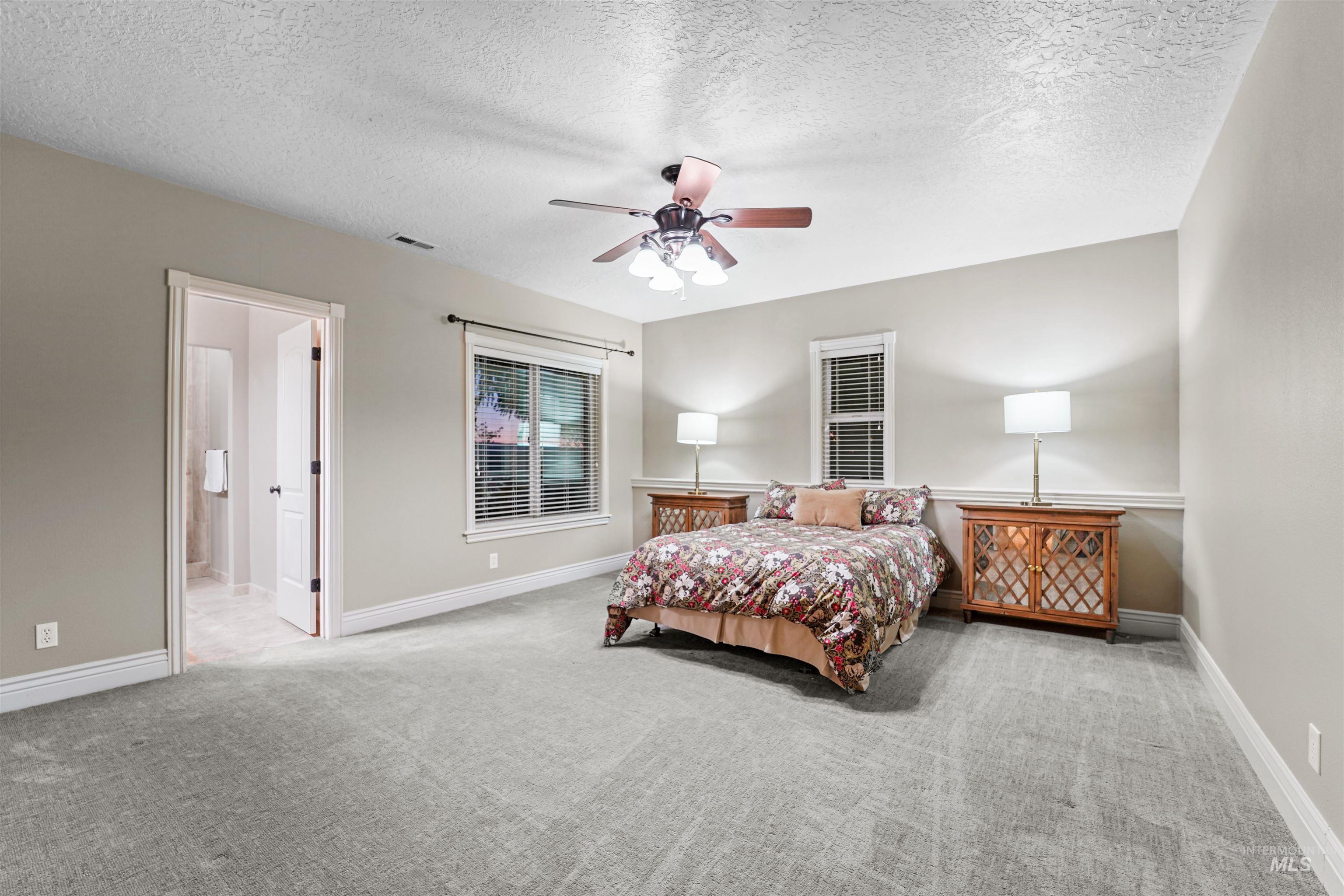 Bedroom featuring carpet, a textured ceiling, ceiling fan, and ensuite bathroom