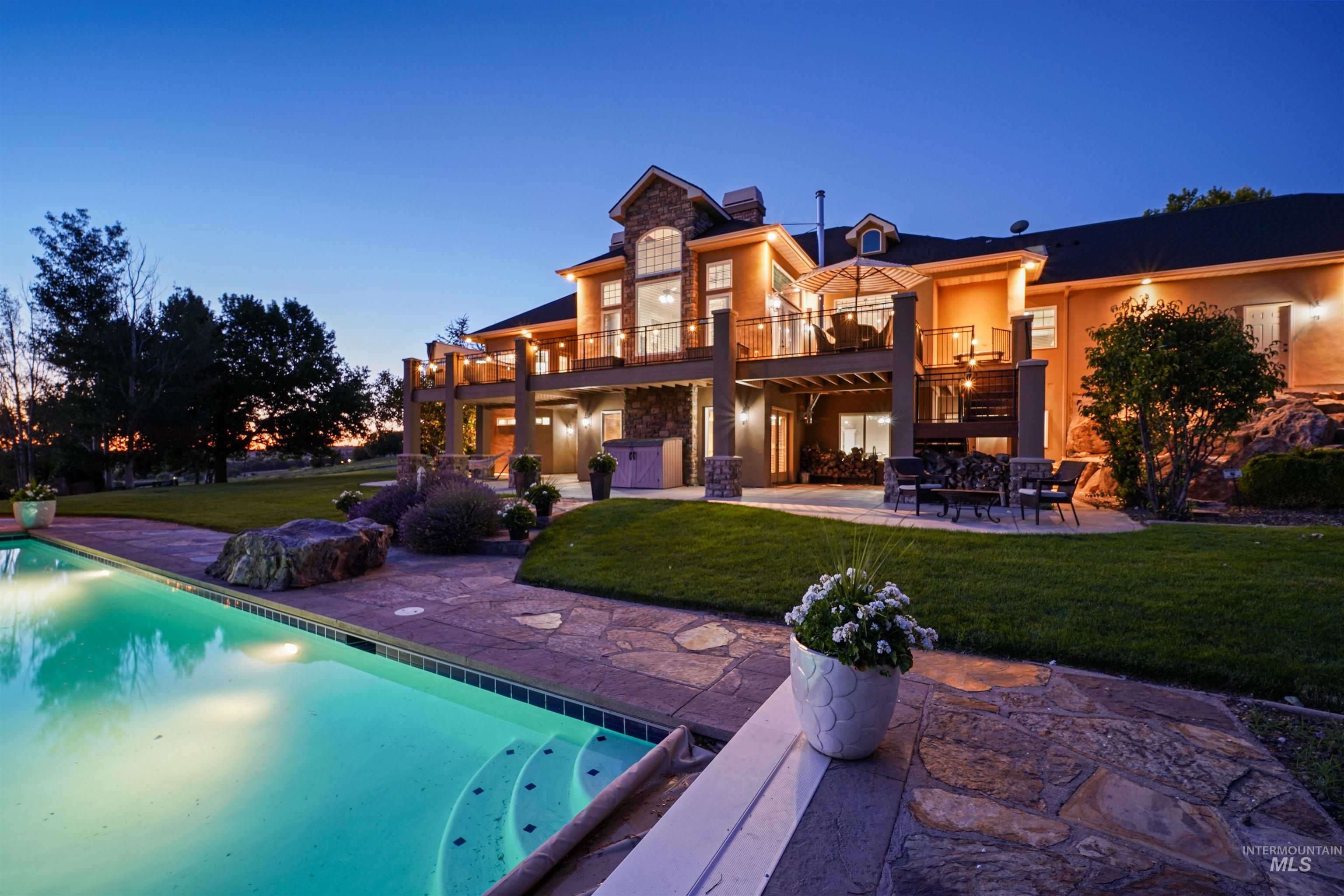 Rear view of property featuring a balcony, a patio area, stone siding, and a yard