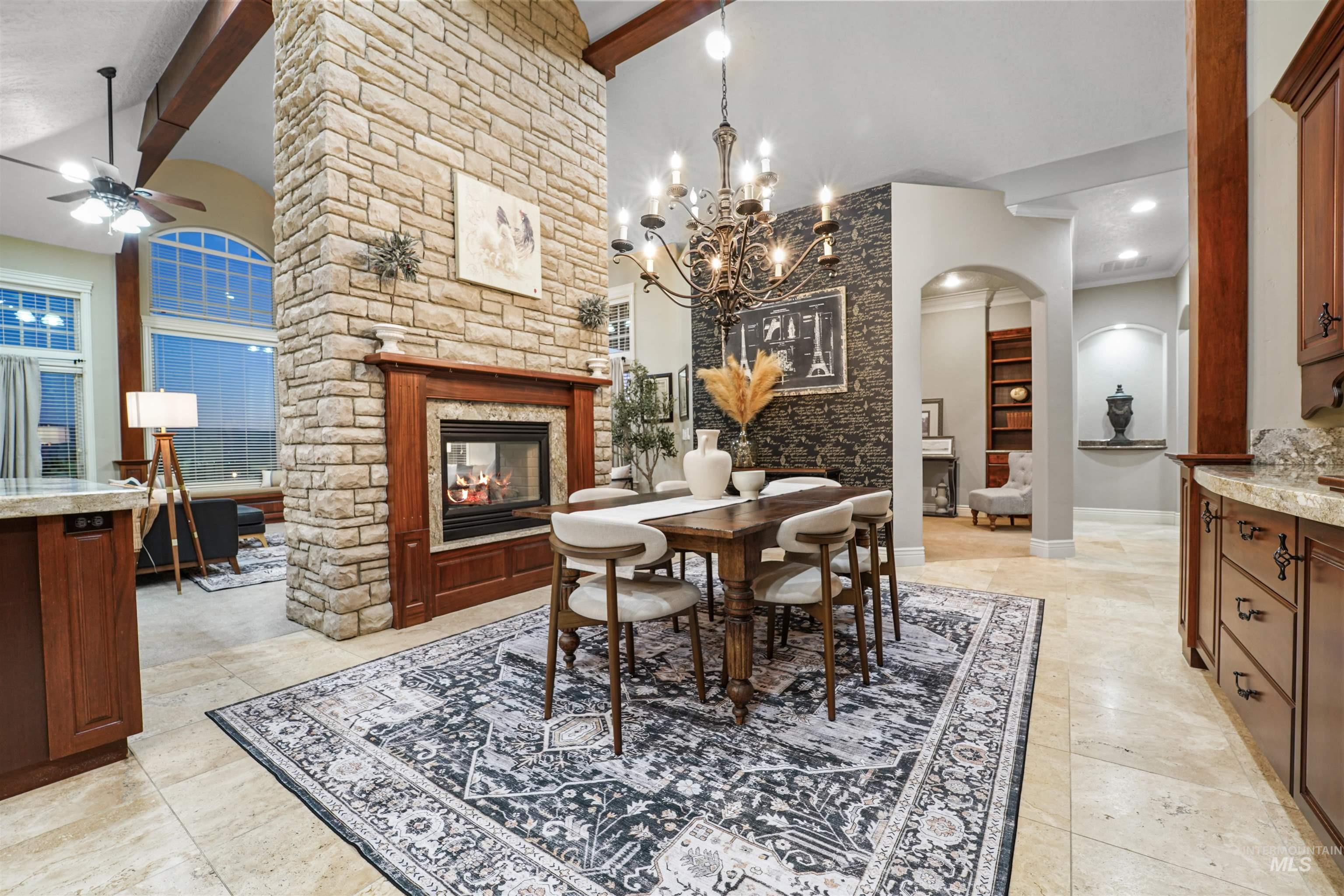 Dining space featuring a stone fireplace, arched walkways, beam ceiling, ceiling fan, and high vaulted ceiling