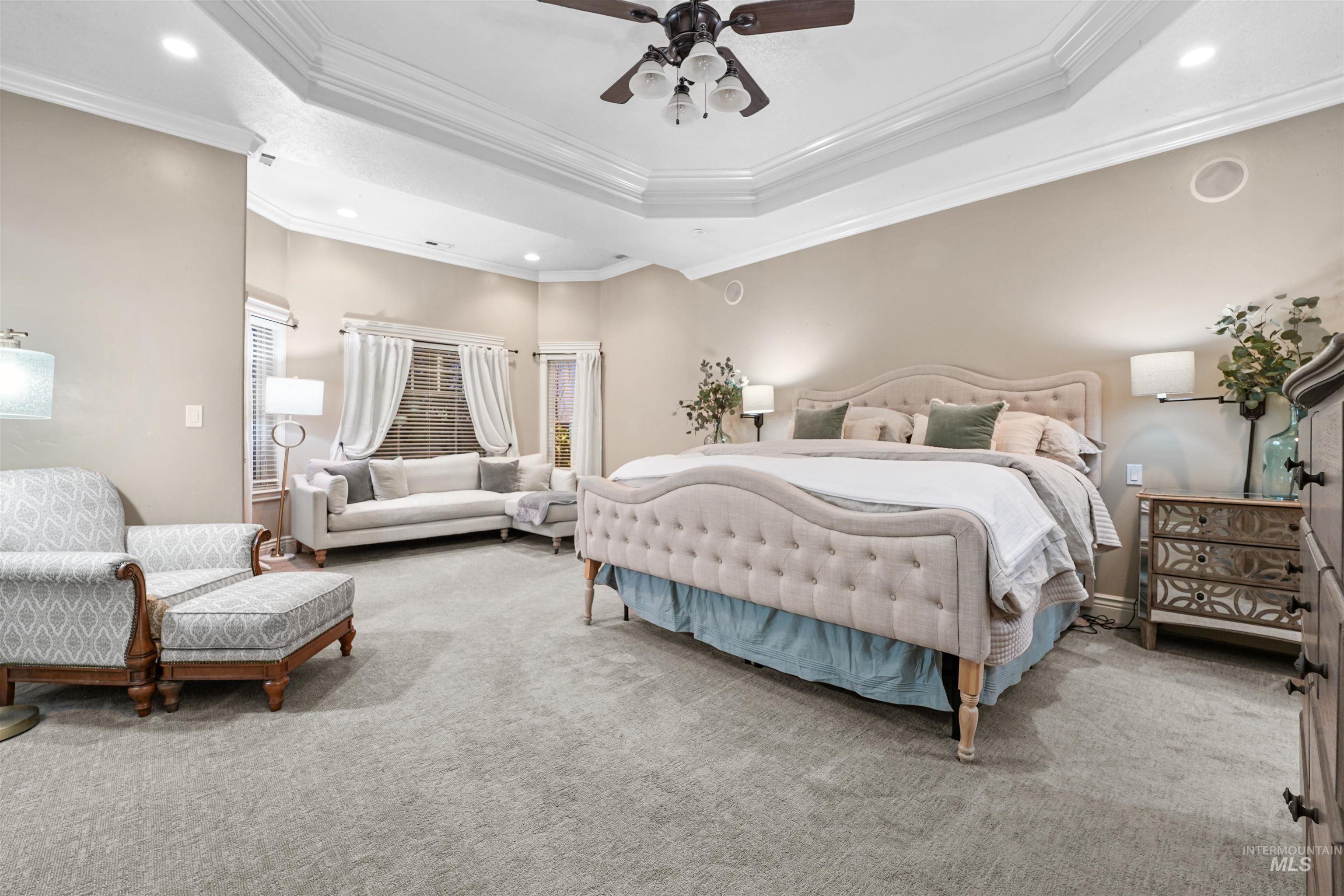 Carpeted bedroom featuring a tray ceiling, crown molding, recessed lighting, and ceiling fan