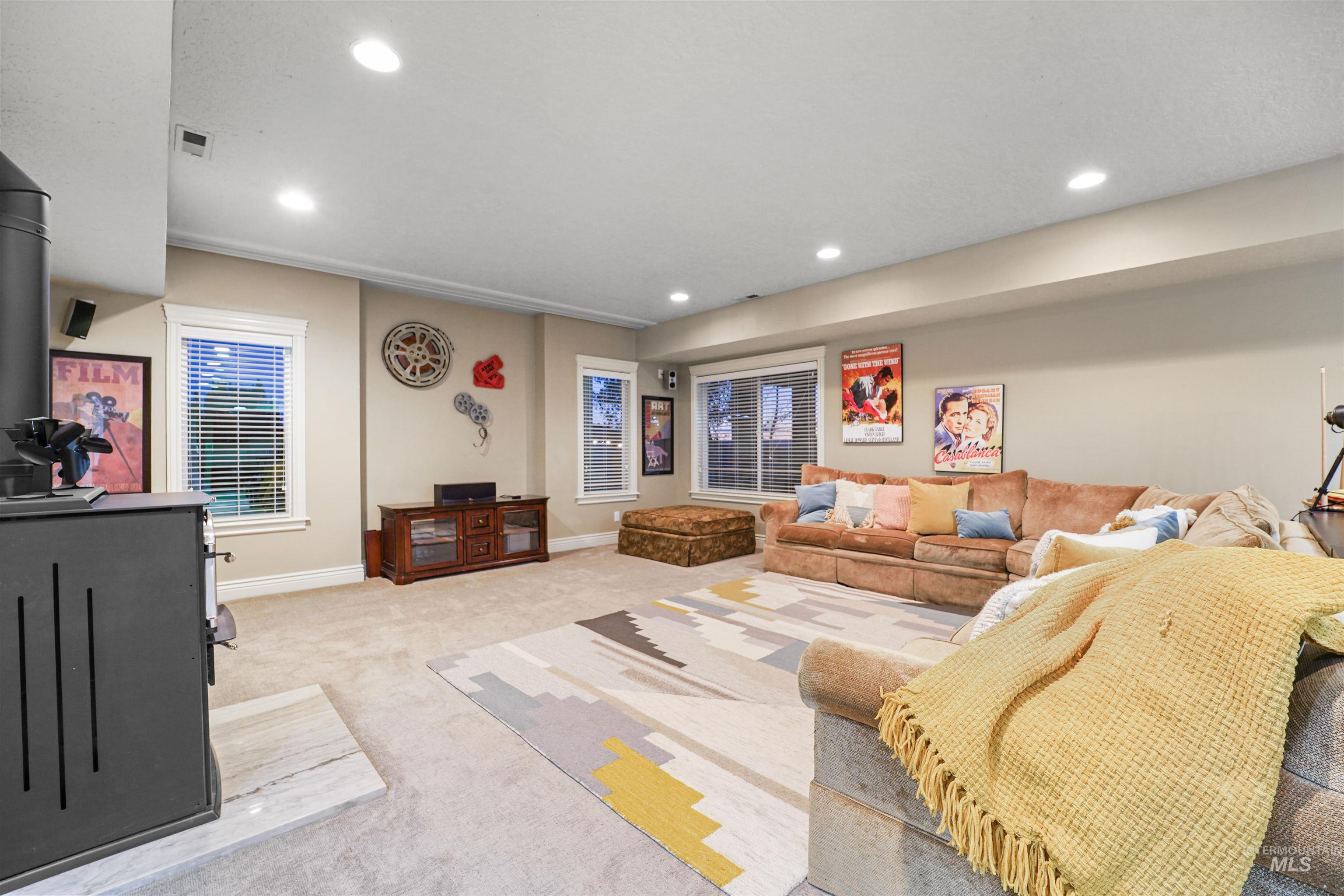 Living area with light colored carpet, recessed lighting, and a wood stove