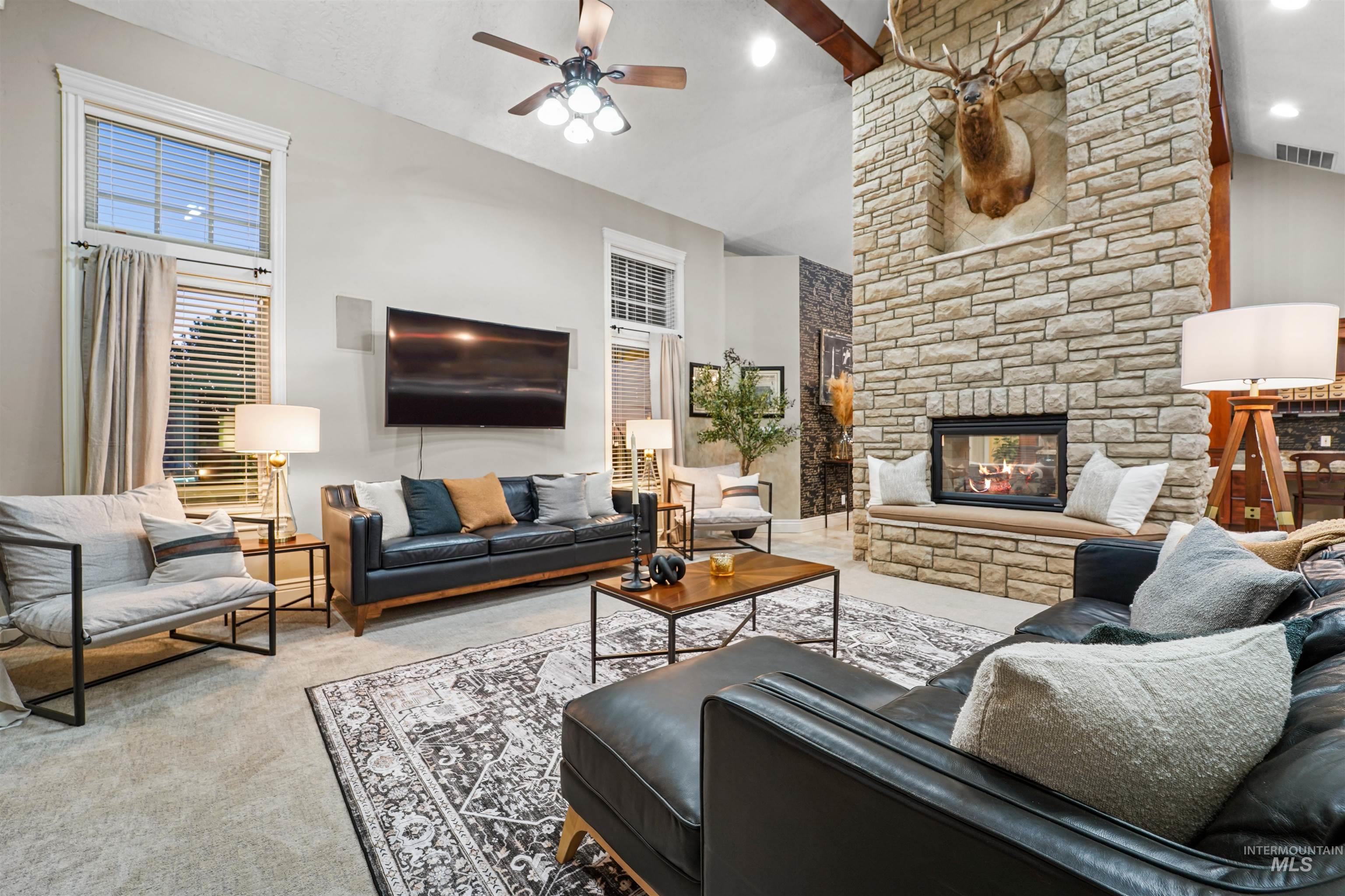 Living room featuring carpet, a ceiling fan, a fireplace, and high vaulted ceiling