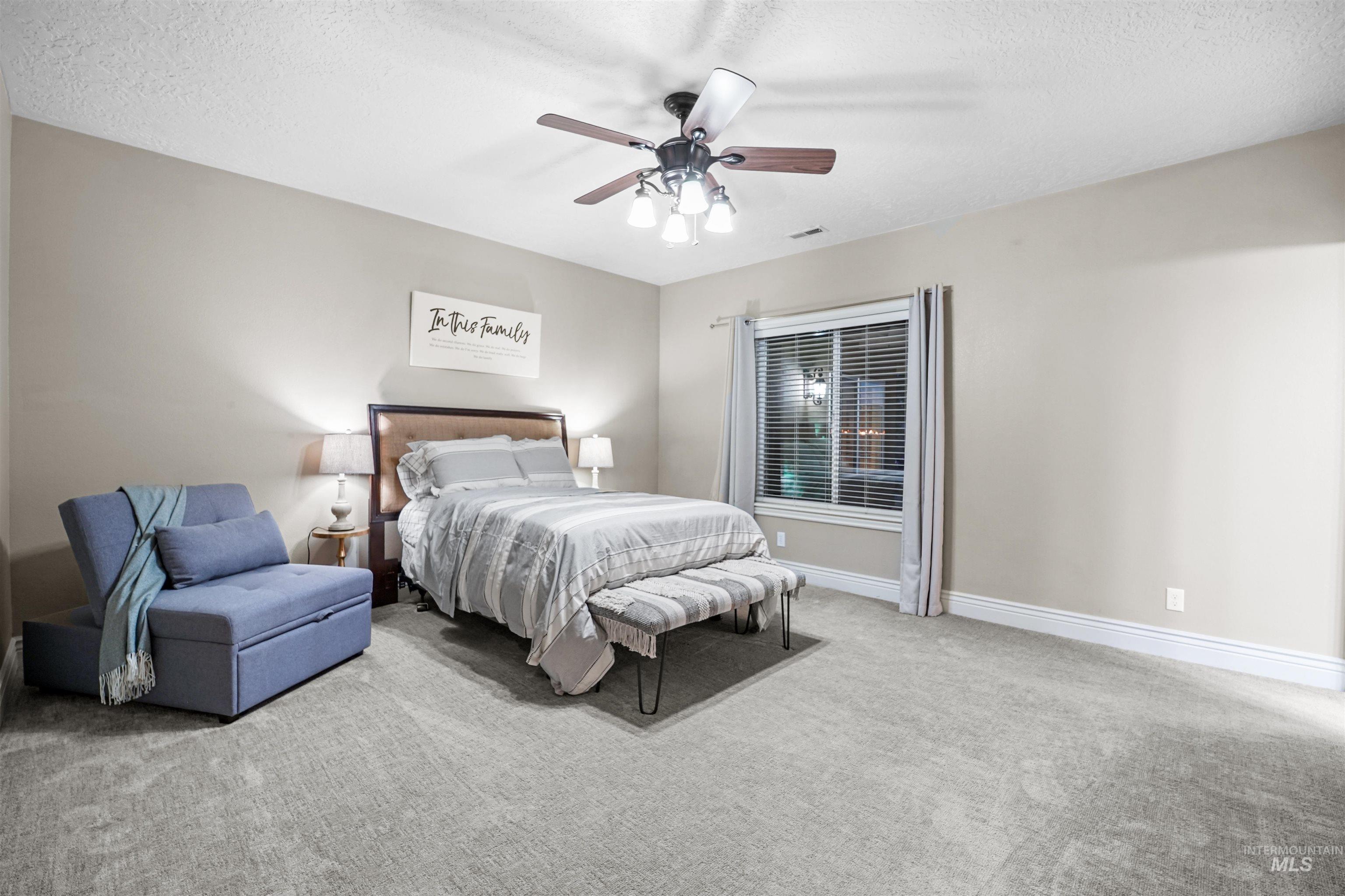 Carpeted bedroom with a textured ceiling and ceiling fan