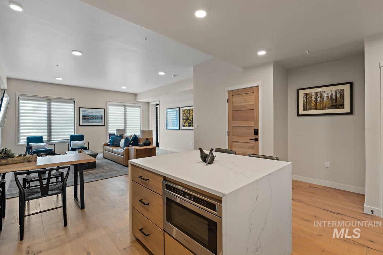 Kitchen with stainless steel microwave, a center island, light wood finished floors, recessed lighting, and open floor plan