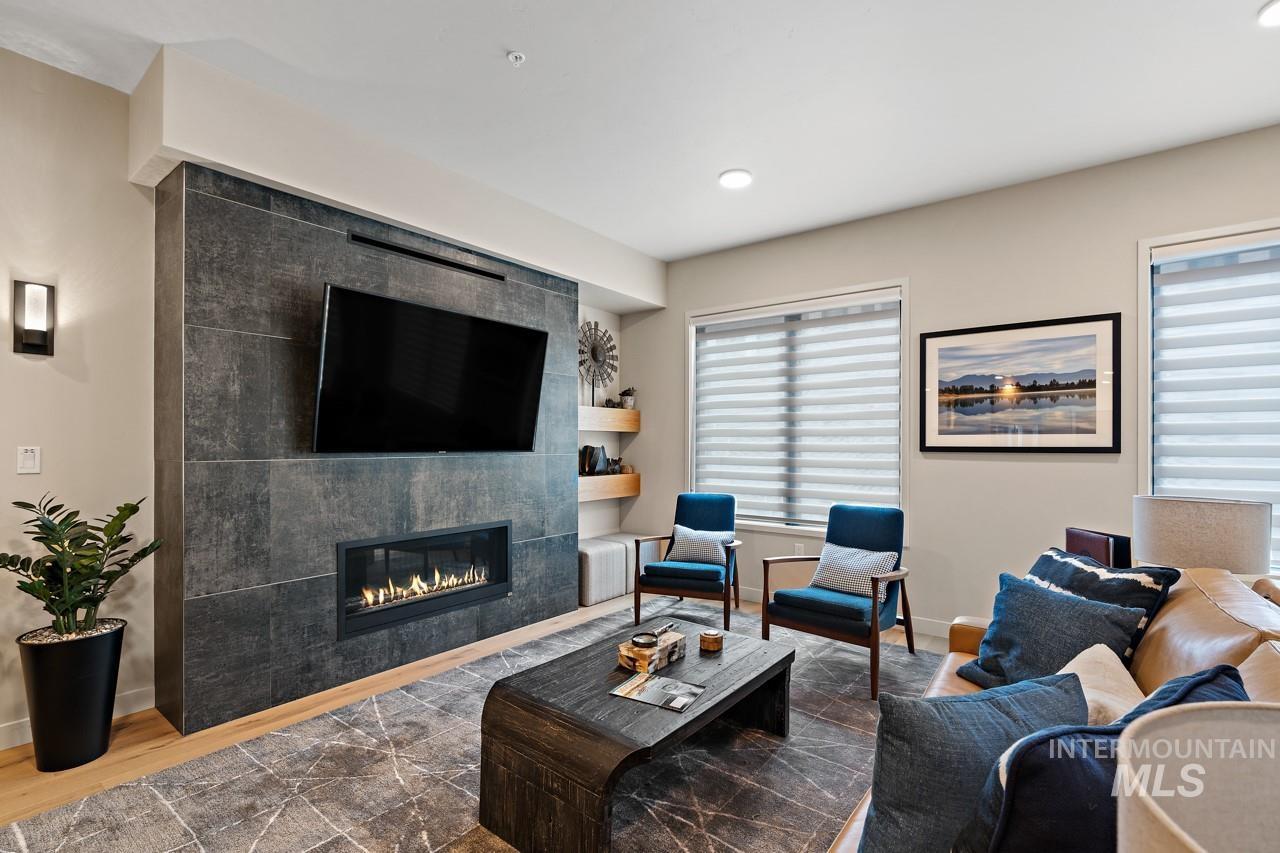 Living area with a tiled fireplace, wood finished floors, and recessed lighting