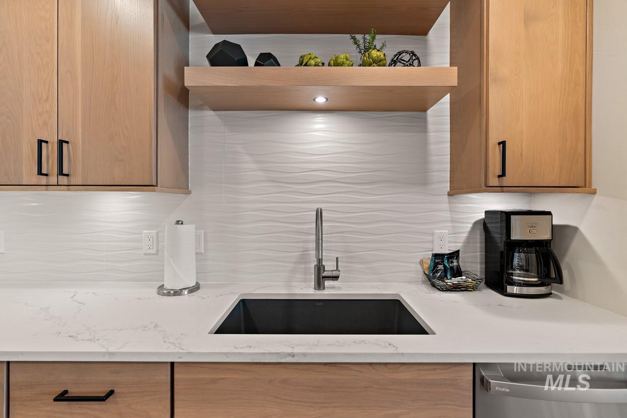 Kitchen with dishwasher, open shelves, tasteful backsplash, and light stone counters