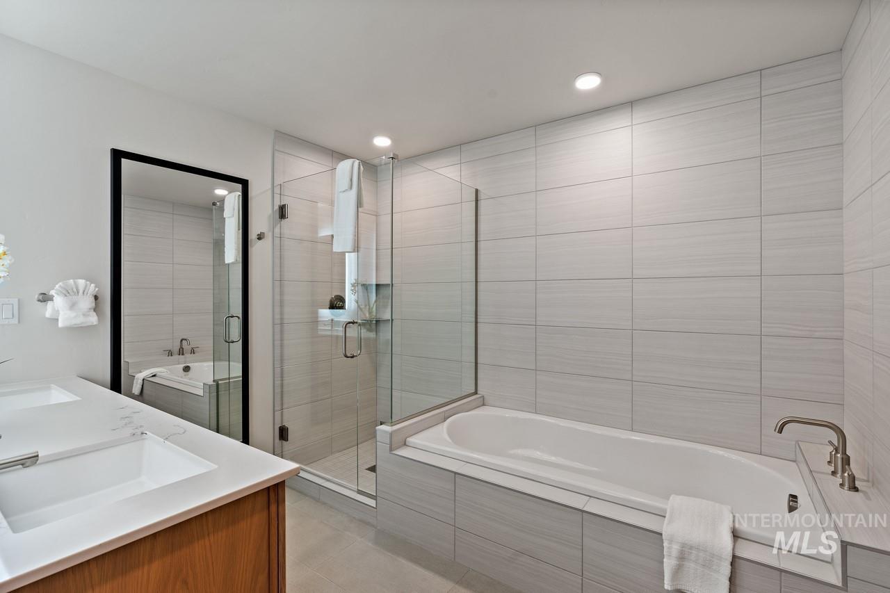 Bathroom featuring double vanity, a stall shower, a garden tub, tile patterned flooring, and recessed lighting