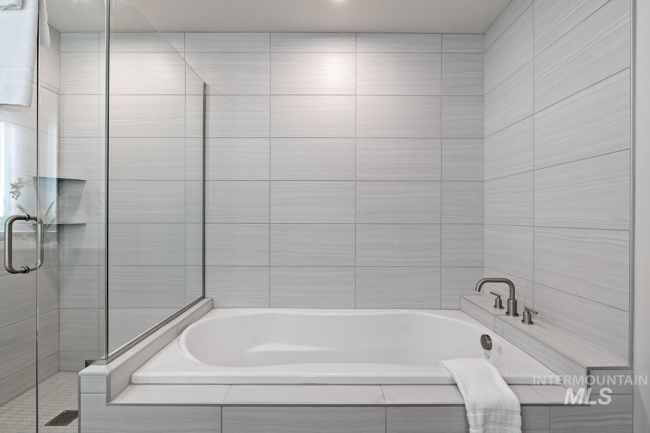 Bathroom featuring a garden tub and a shower stall