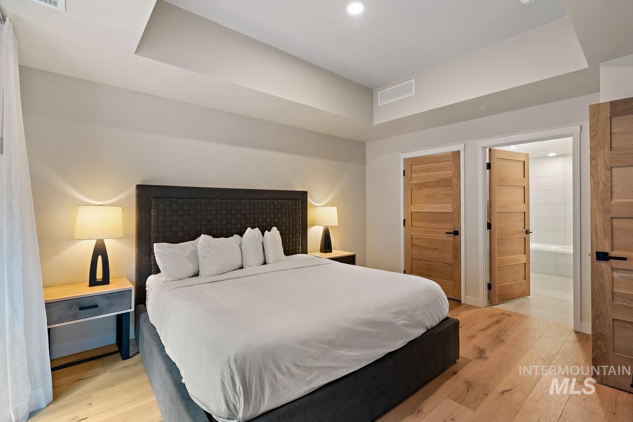 Bedroom with light wood-style floors, recessed lighting, and connected bathroom