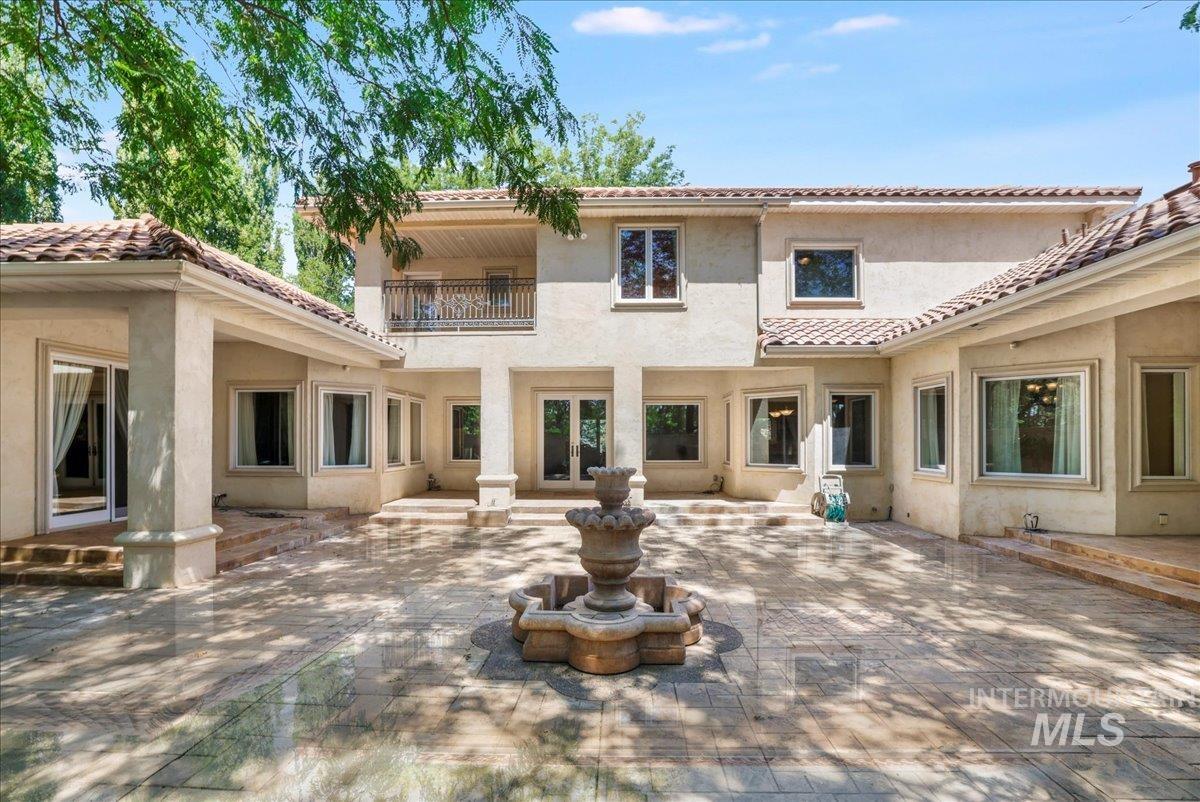 Back of house with a patio, stucco siding, a balcony, a tile roof, and french doors