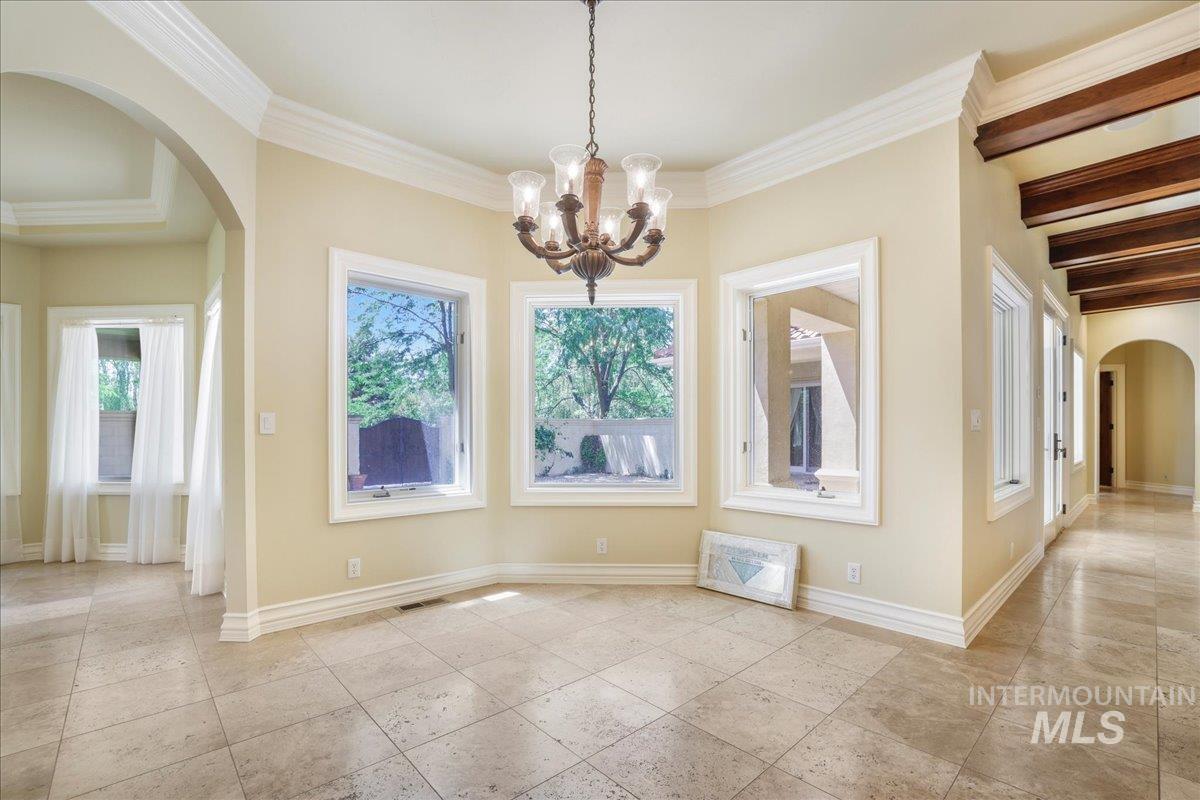 Unfurnished dining area featuring arched walkways, a chandelier, and ornamental molding