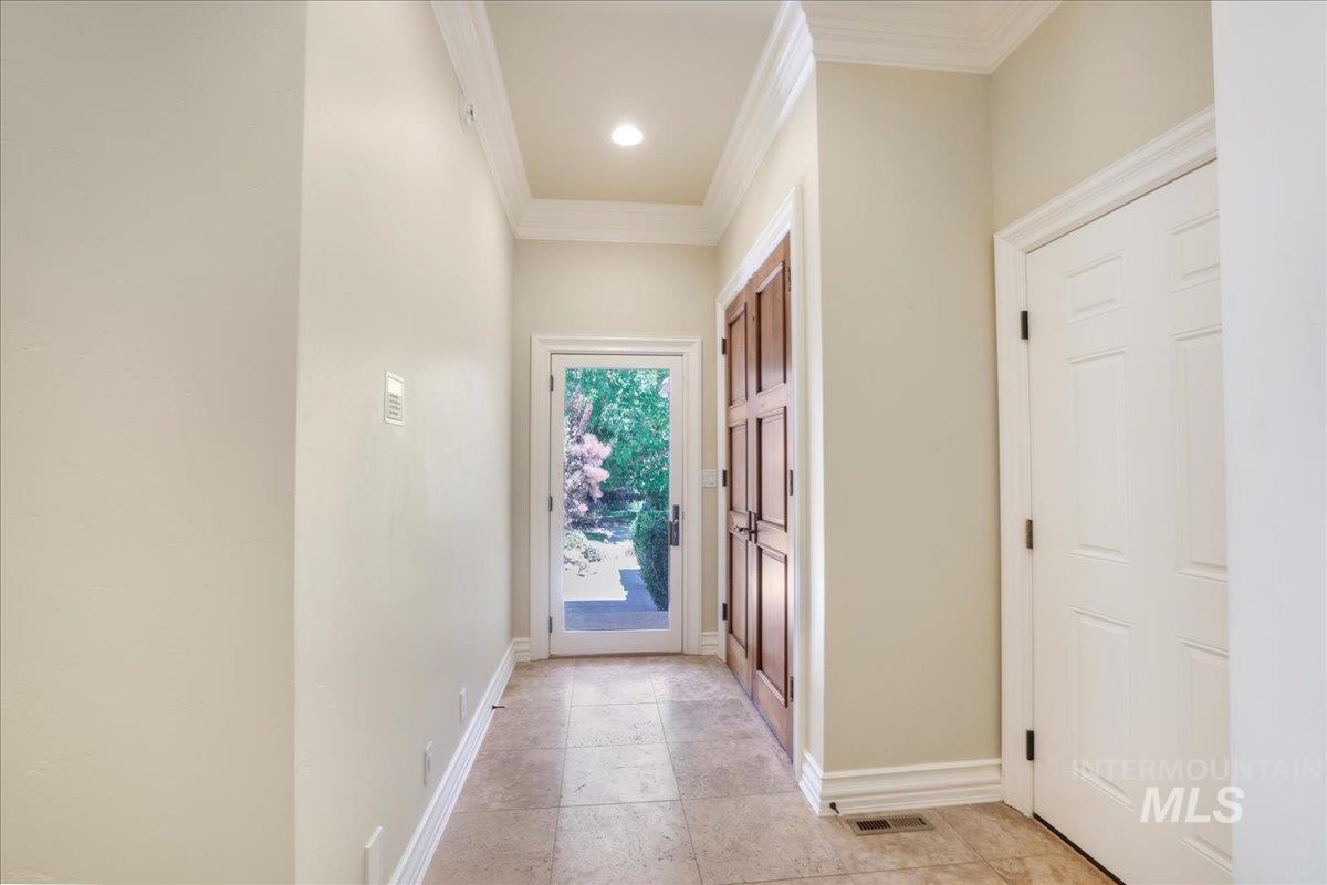 Corridor with crown molding and baseboards