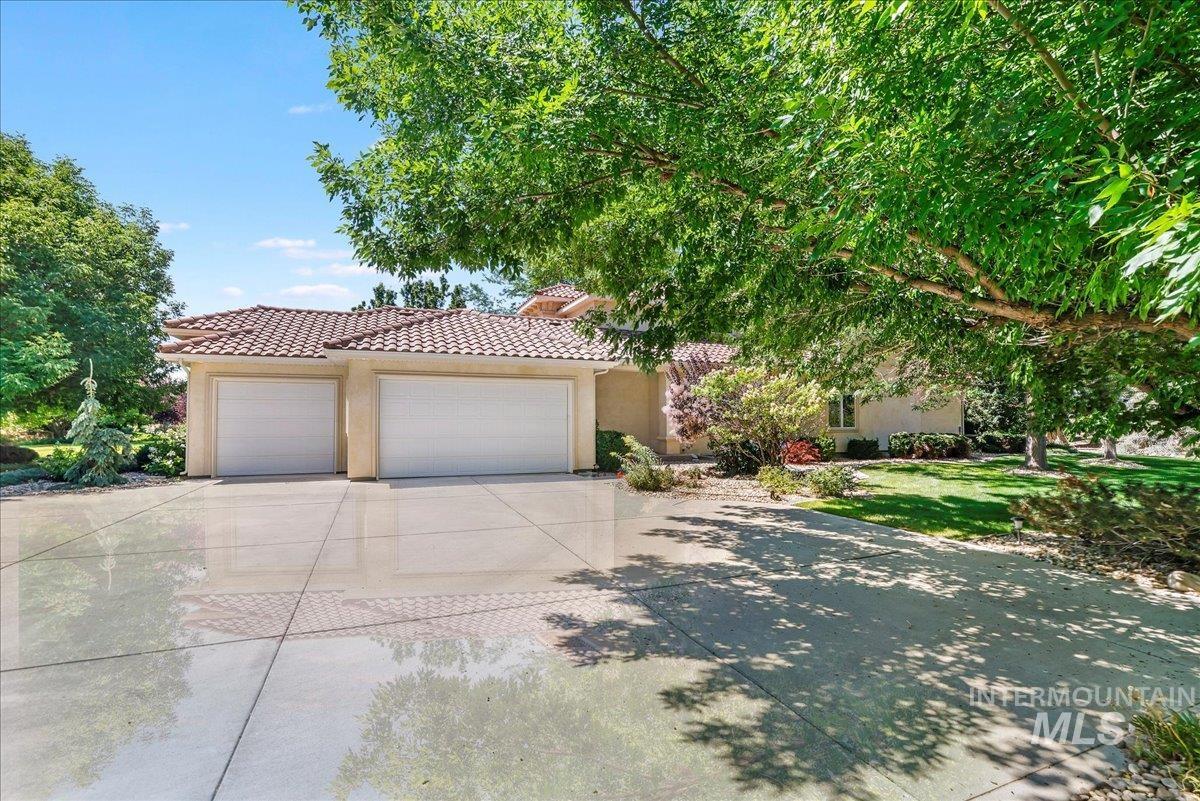 View of front of home with driveway, a garage, stucco siding, a tiled roof, and a front lawn