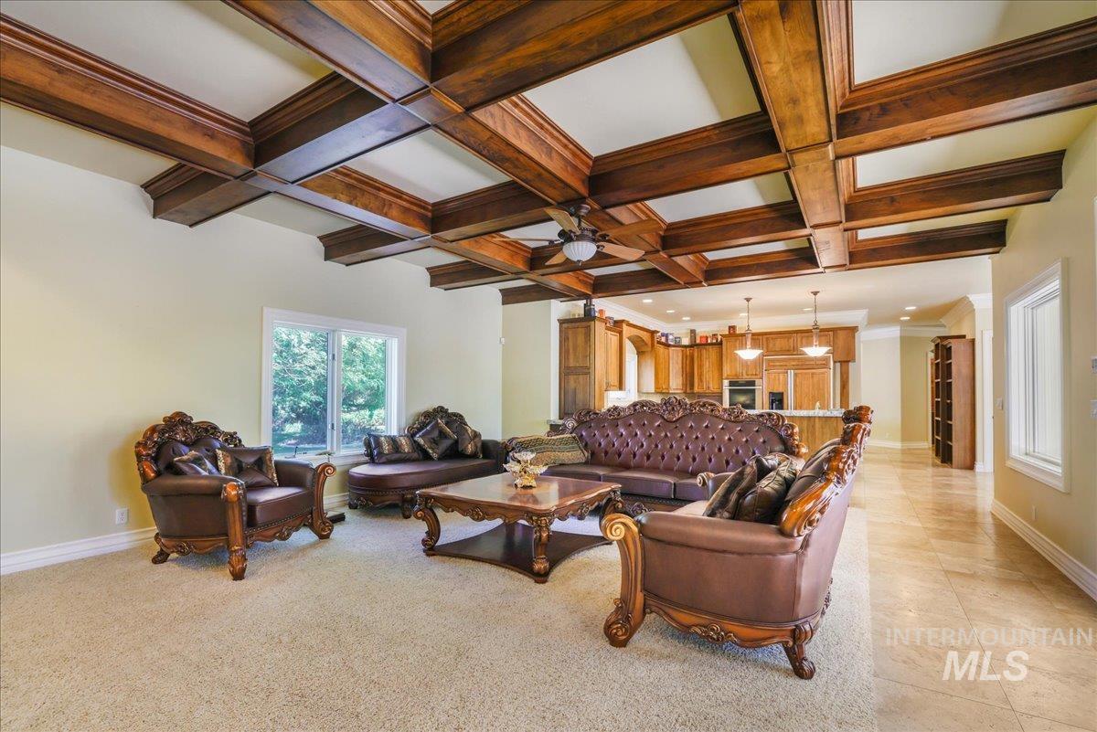 Living area featuring healthy amount of natural light, ceiling fan, beamed ceiling, coffered ceiling, and light tile patterned floors