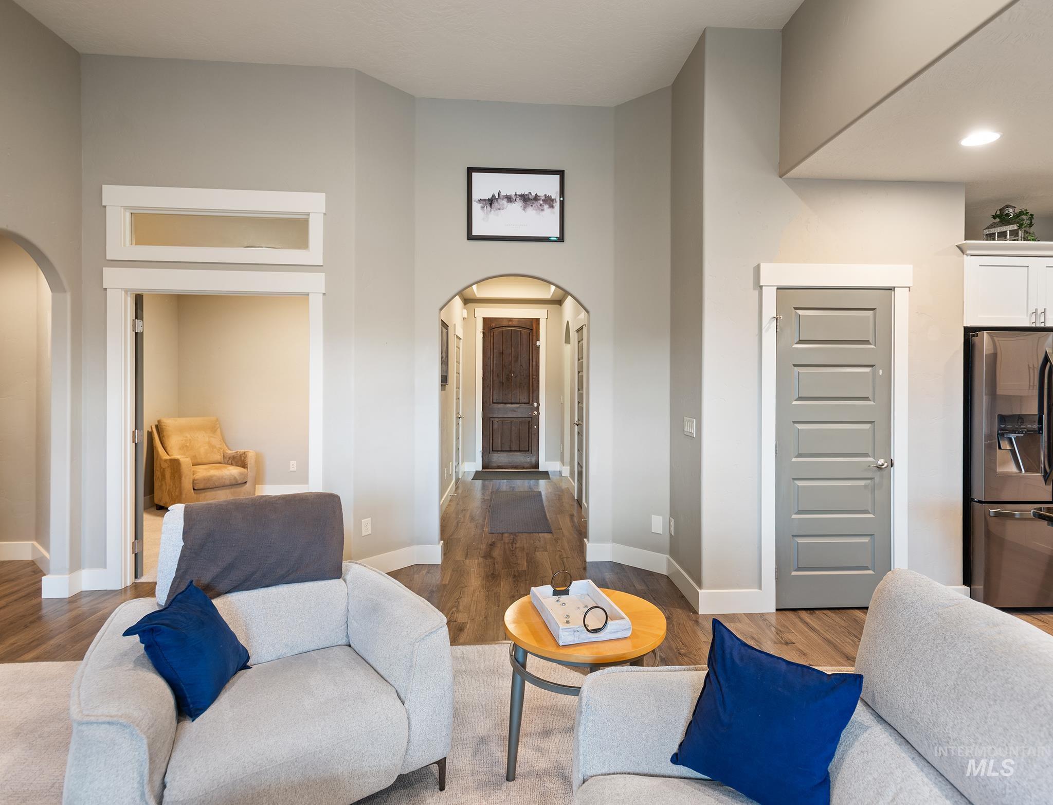 Living area with arched walkways, wood finished floors, and a towering ceiling