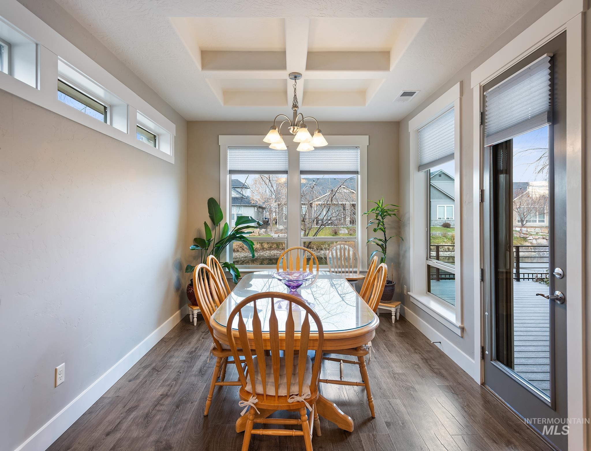 Dining area with a chandelier, plenty of natural light, and dark wood finished floors