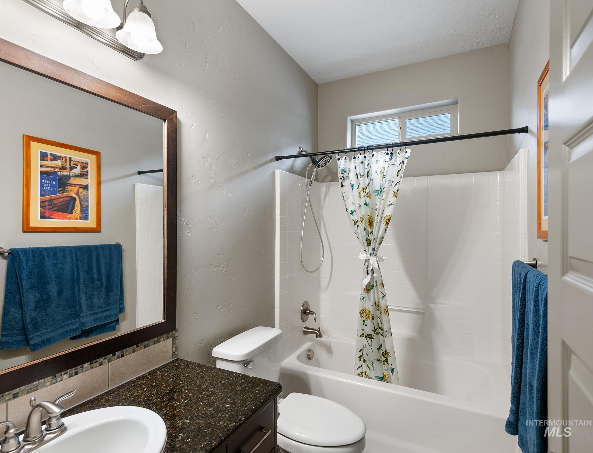 Bathroom featuring shower / bathtub combination with curtain, vanity, and a textured wall