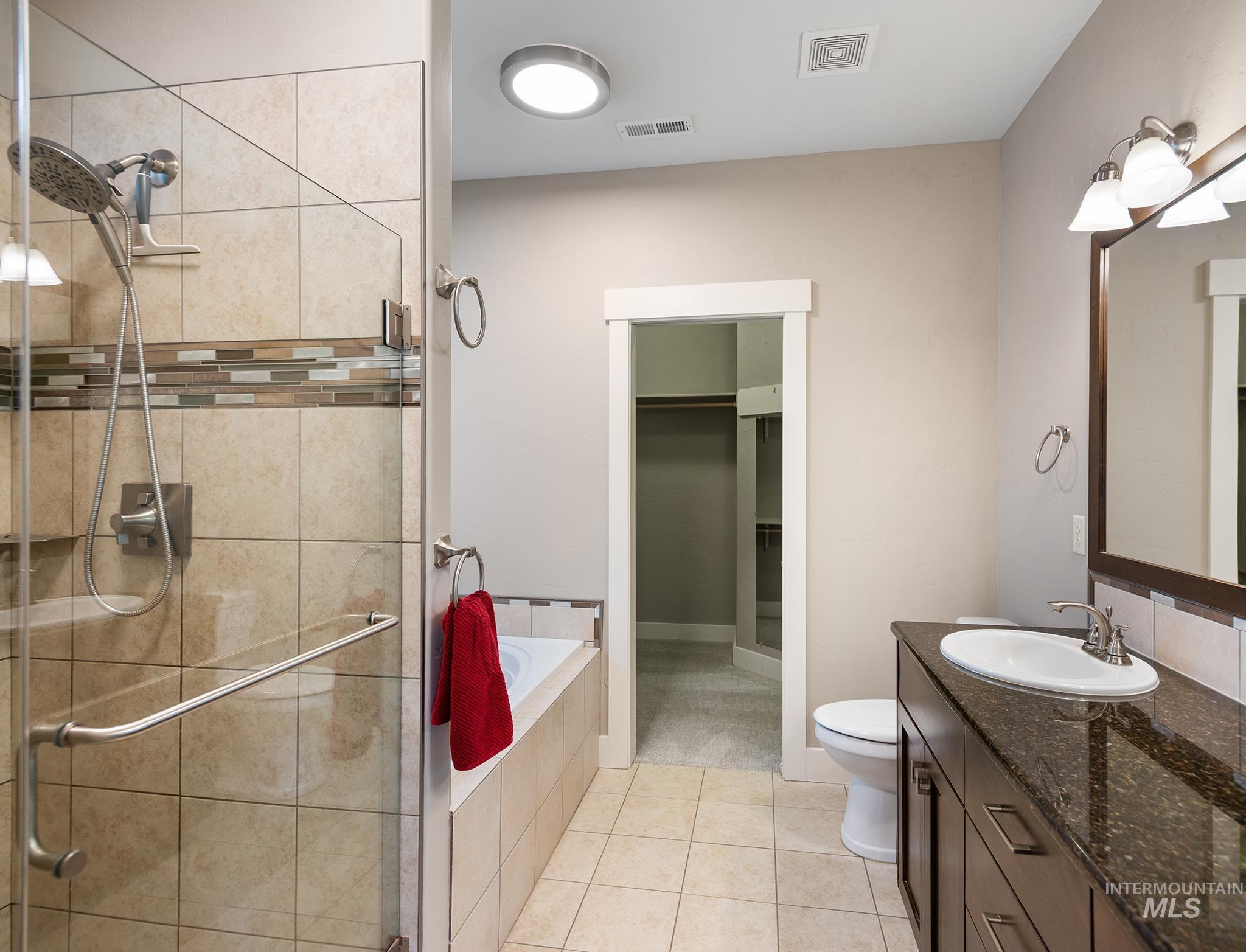 Bathroom with vanity, a walk in closet, a shower stall, and a garden tub