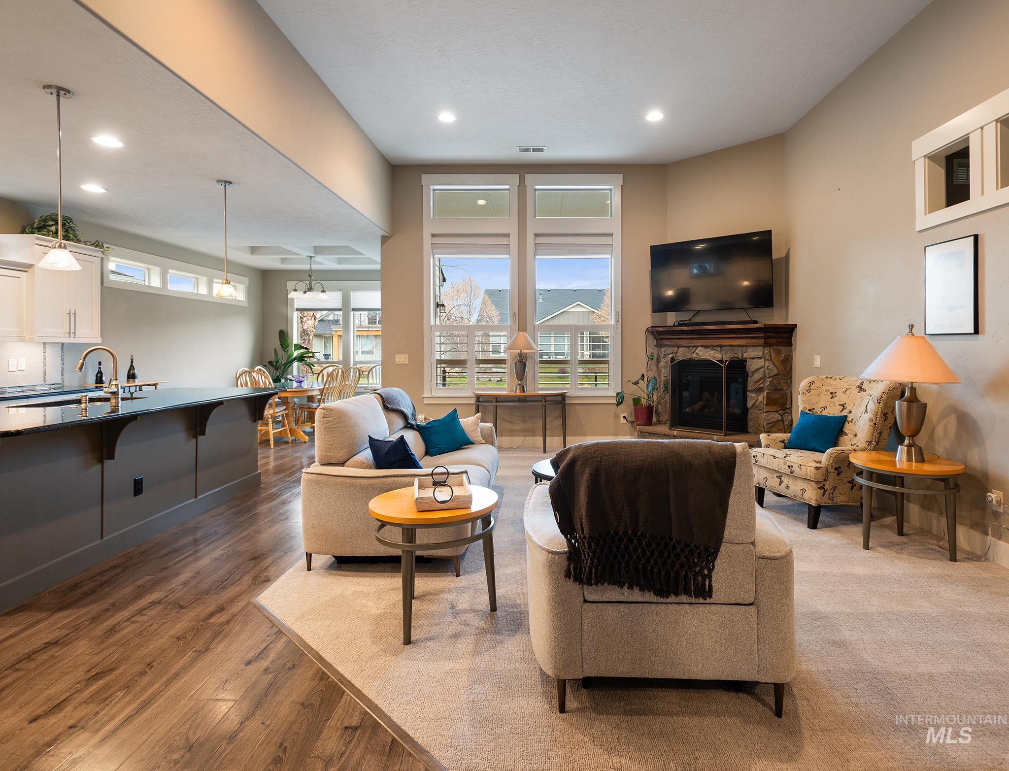 Living area featuring a stone fireplace, plenty of natural light, recessed lighting, and dark wood-style floors