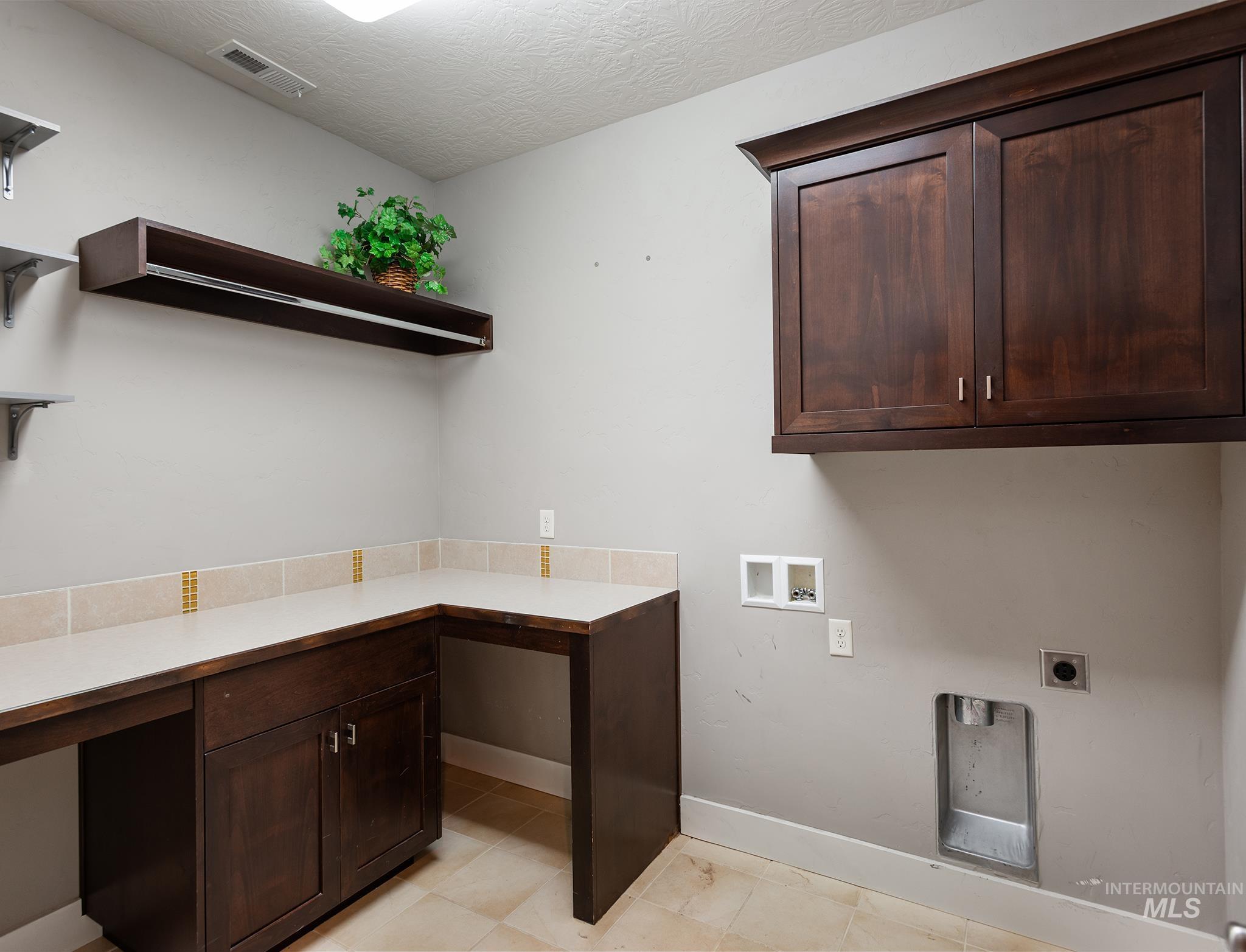 Washroom featuring hookup for a washing machine, cabinet space, electric dryer hookup, an office area, and a textured ceiling