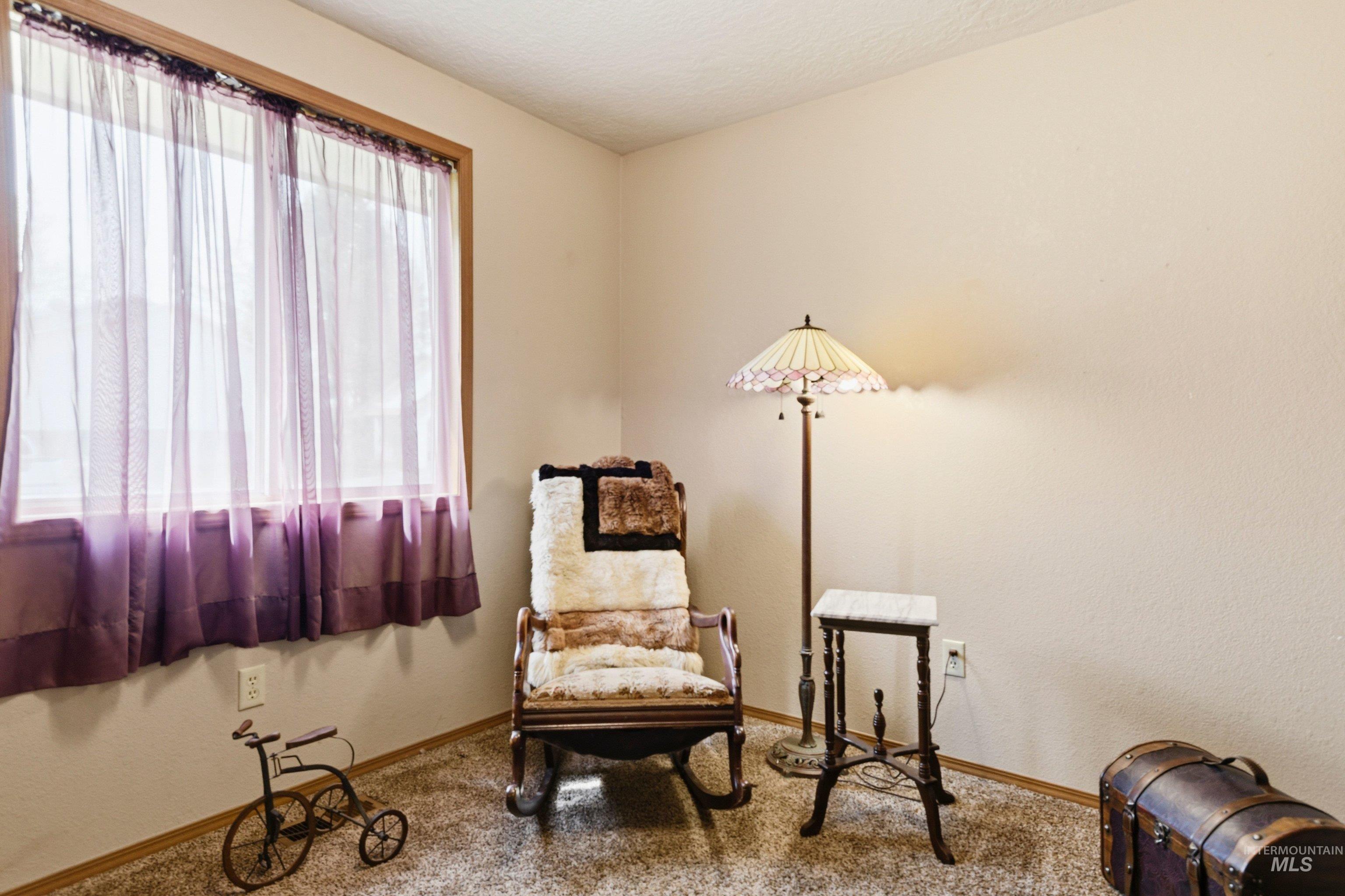 Living area featuring a textured ceiling, carpet, and a textured wall