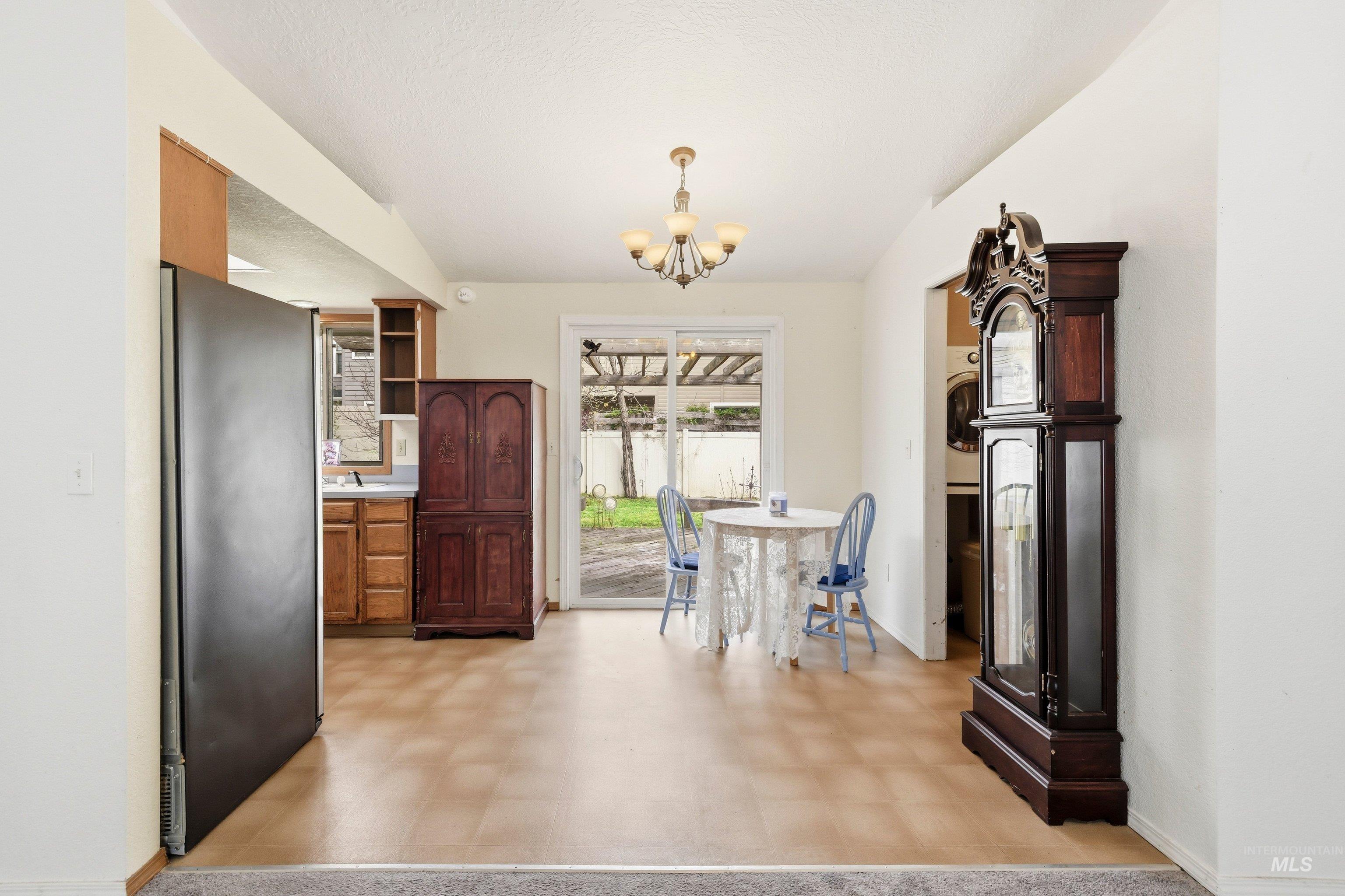 Kitchen featuring light floors, freestanding refrigerator, light countertops, open shelves, and hanging lights