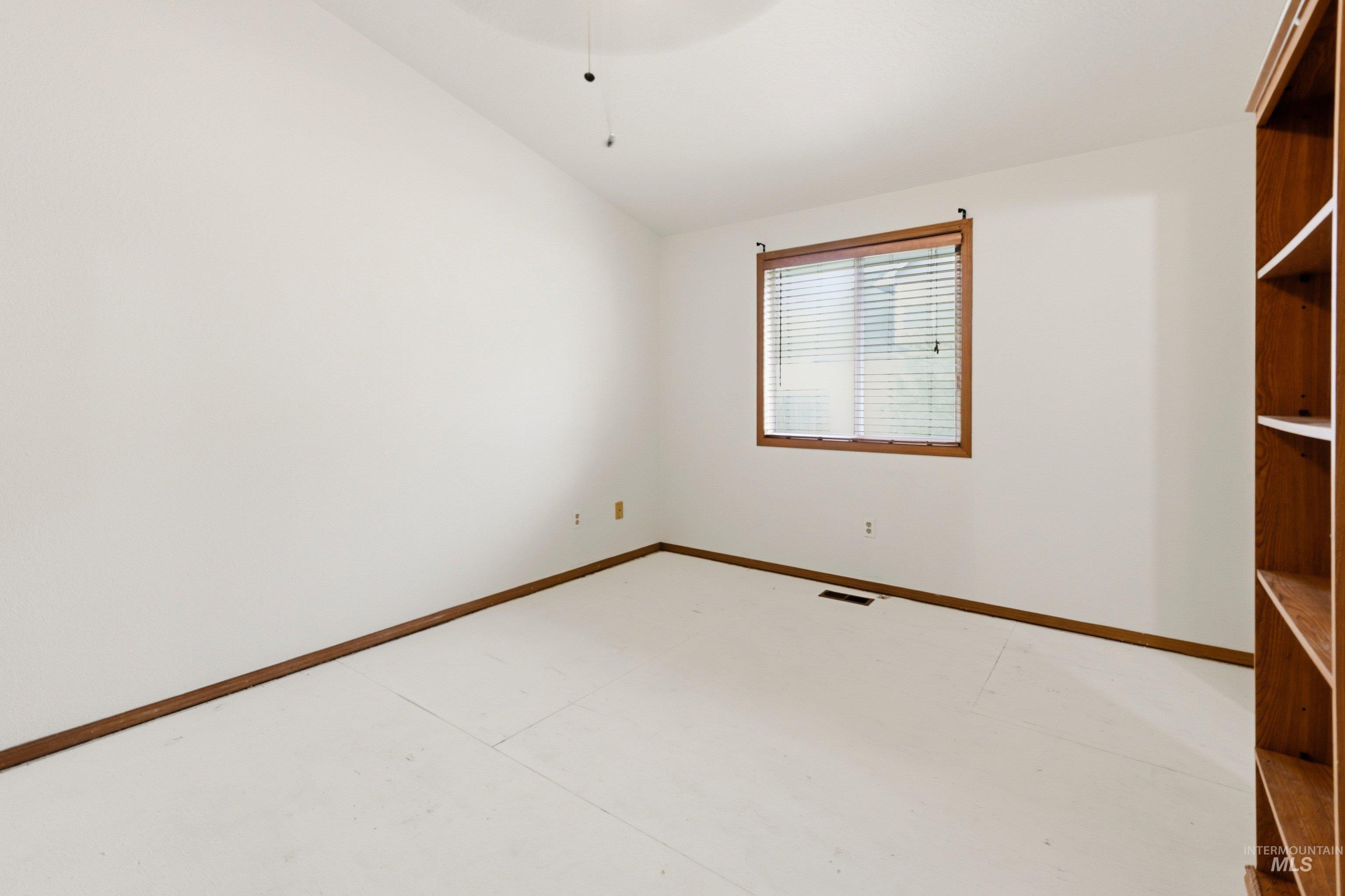 Unfurnished room with lofted ceiling and baseboards