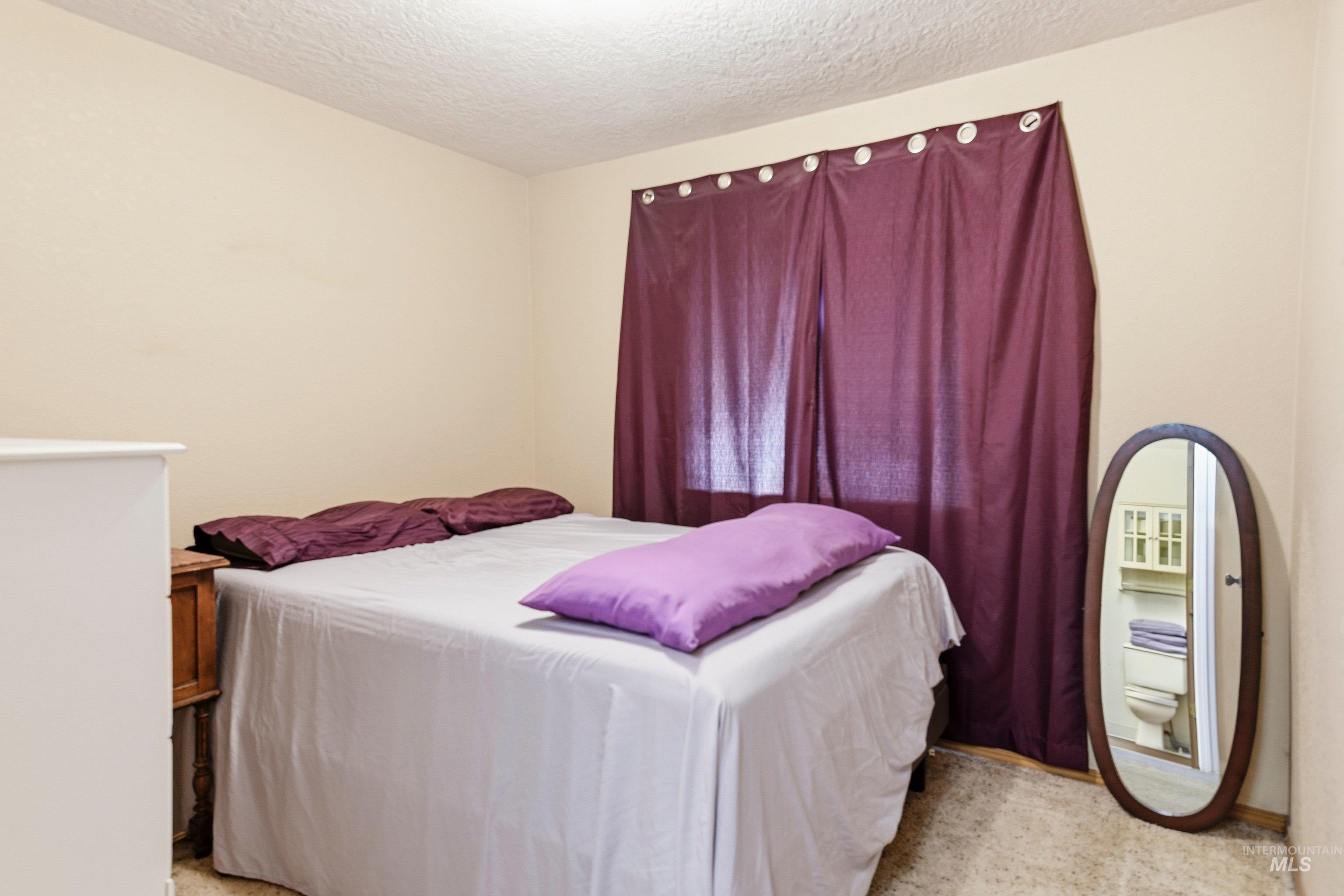 Bedroom with a textured ceiling and light carpet