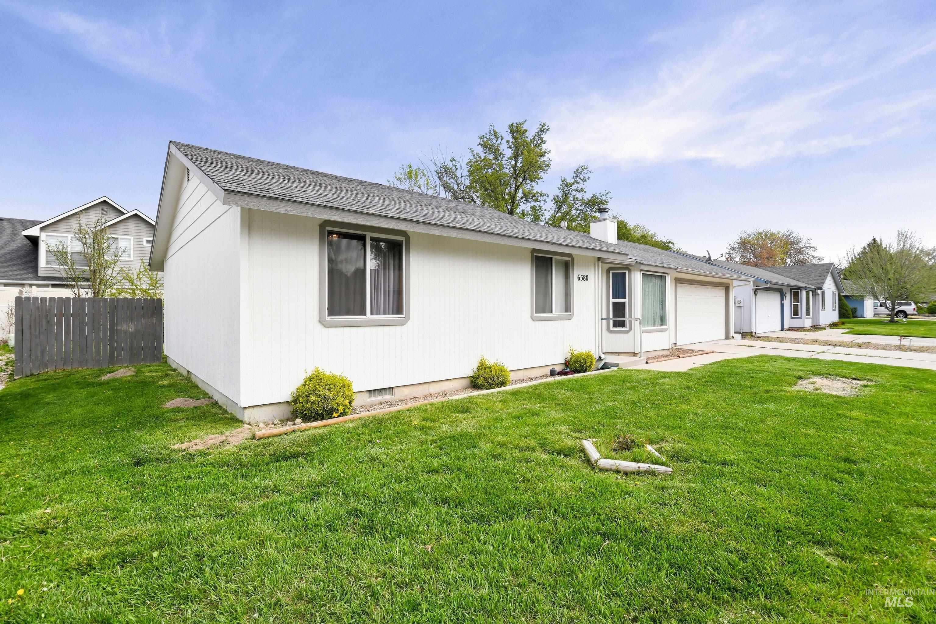 Single story home with a garage, a chimney, driveway, and a shingled roof