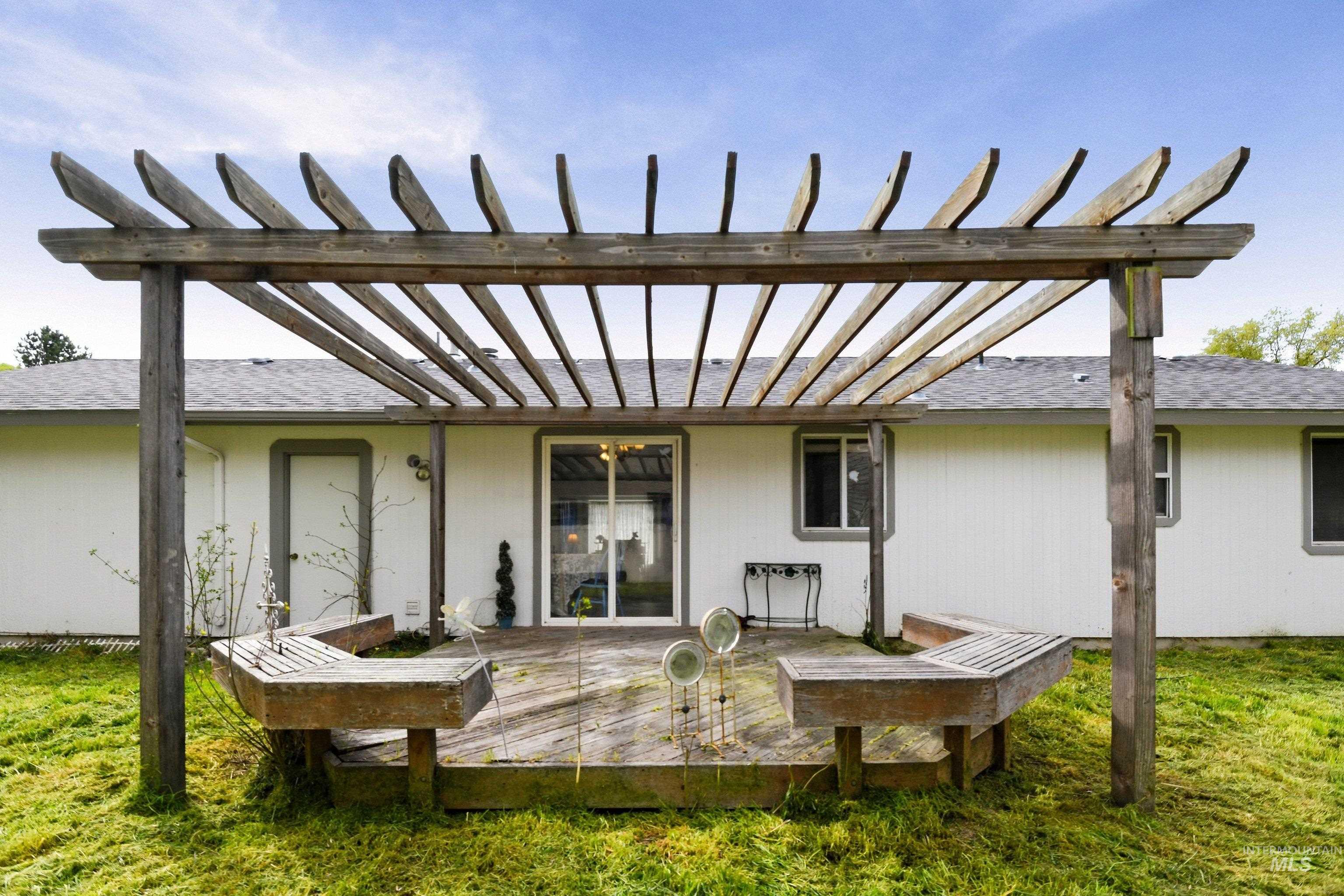 Back of property featuring a yard, a pergola, and a shingled roof