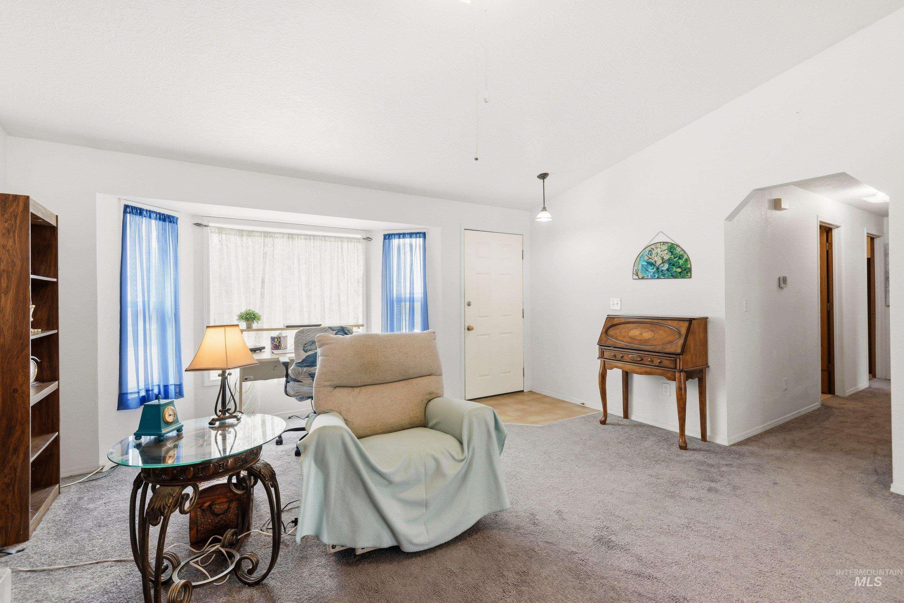 Living area with lofted ceiling, light colored carpet, and arched walkways