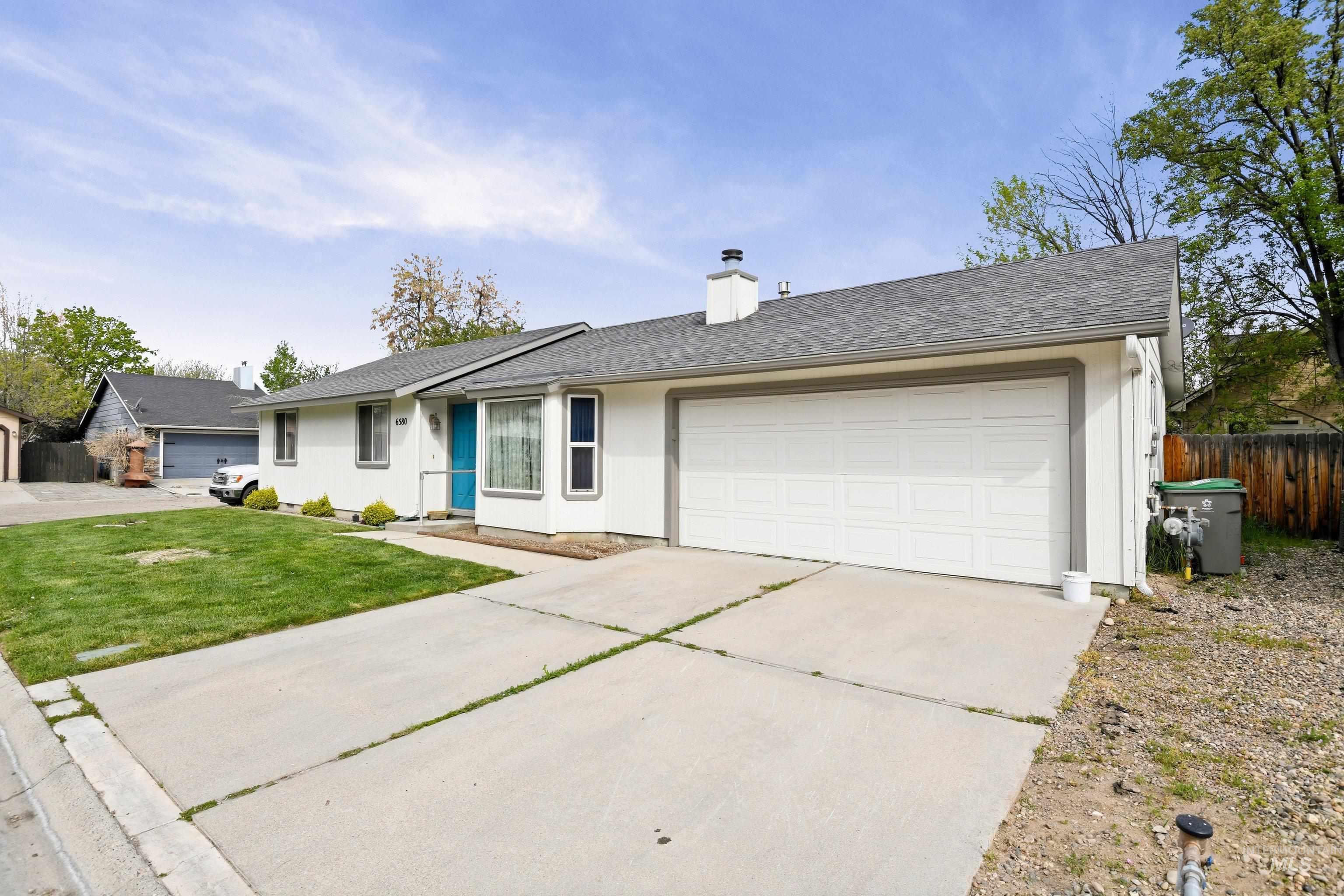 Single story home featuring a shingled roof, a chimney, driveway, and a garage