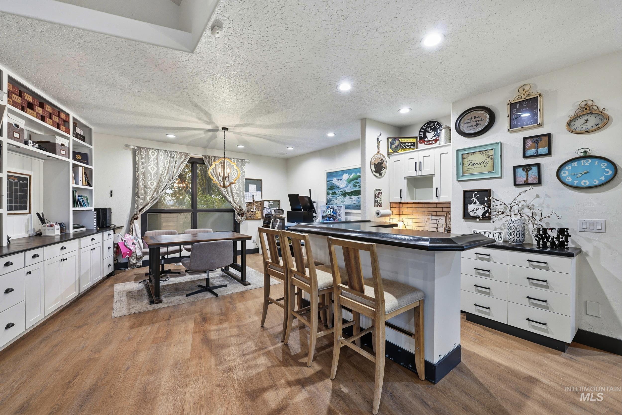 Kitchen with white cabinets, a textured ceiling, open shelves, decorative light fixtures, and light wood finished floors