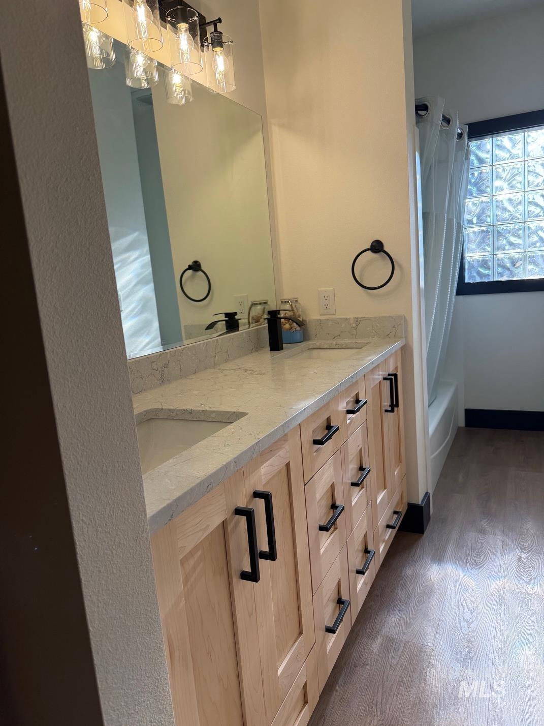 Full bathroom with vanity, dark wood-type flooring, and shower / bathtub combination with curtain