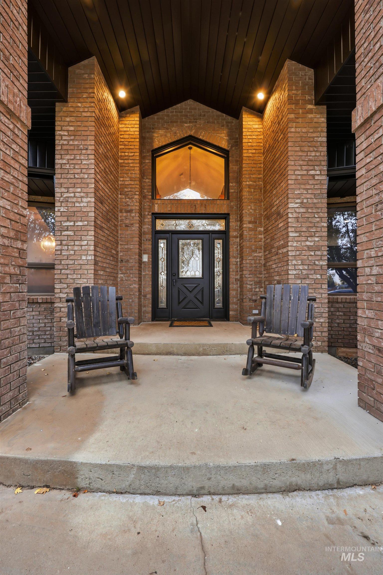 Doorway to property with brick siding and a patio